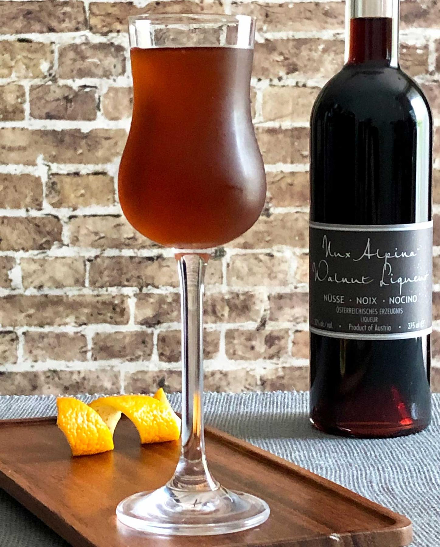 An example of the Mississauga Cocktail, the mixed drink (drink) featuring rye whiskey, Nux Alpina Walnut Liqueur, simple syrup, Angostura bitters, orange bitters, and orange twist; photo by Lee Edwards