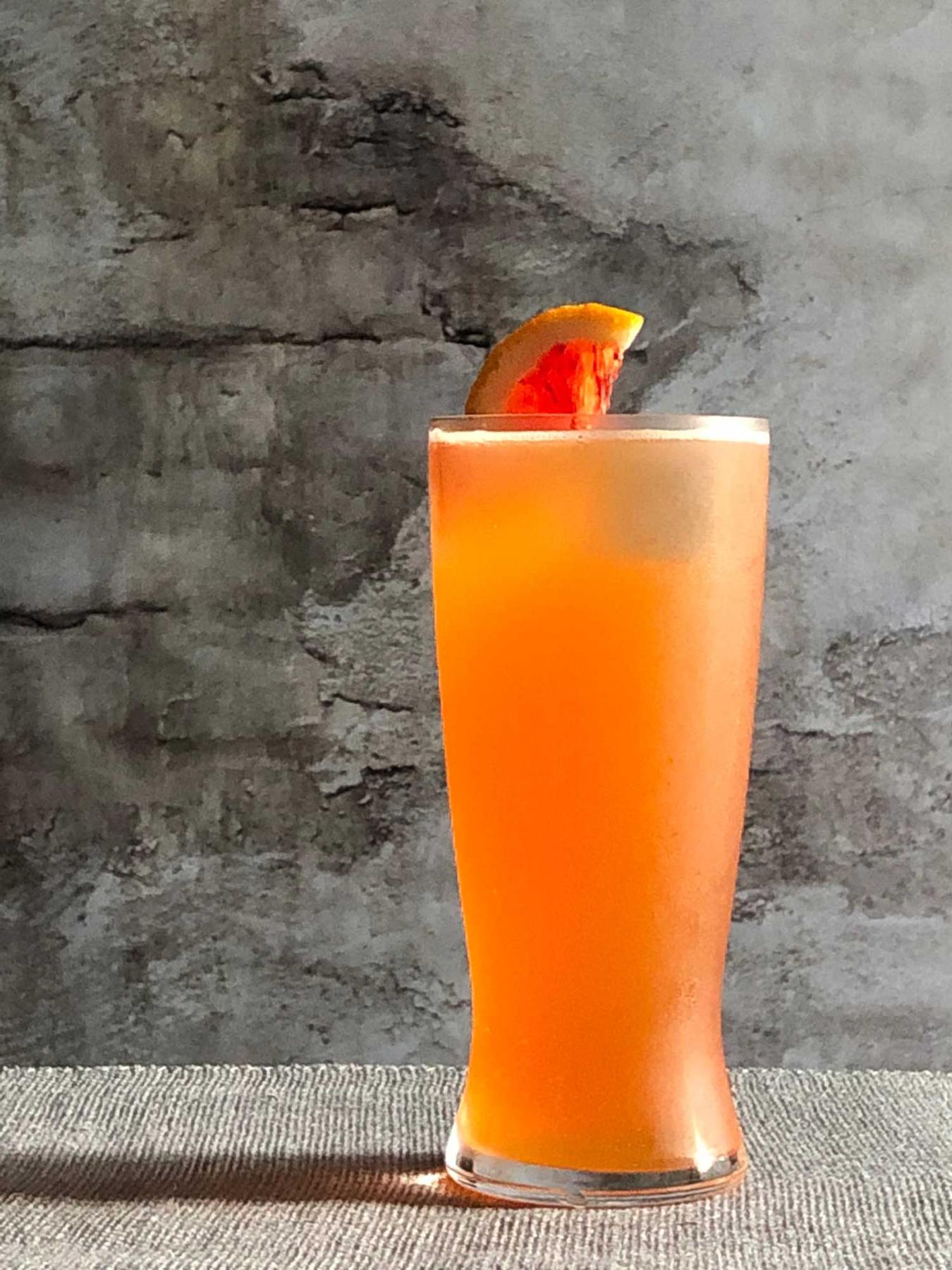 An example of the The Roadie, the mixed drink (drink), by Booth Hardy, Barrel Thief Wine Shop & Café, Richmond, VA. In honor of the 2015 World Road Cycling Championships, featuring Stiegl Grapefruit Radler, Aperitivo Cappelletti, ice cubes, and orange wheel; photo by Lee Edwards