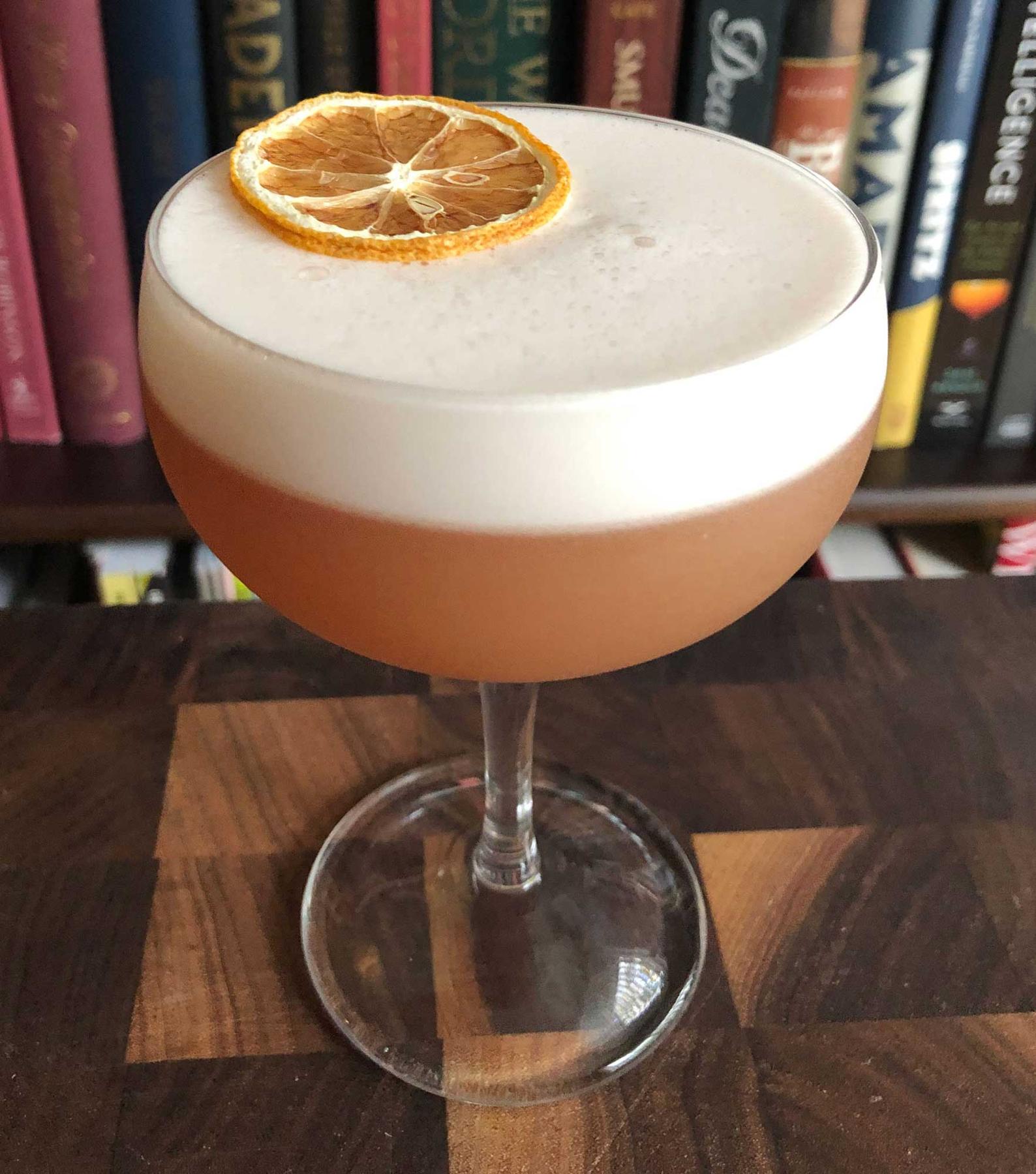 An example of the Savoy Tango Sour, the mixed drink (drink), variation of a drink from the Savoy Cocktail Book, featuring lemon juice, egg white, Hayman’s Sloe Gin, apple brandy, and simple syrup; photo by Lee Edwards