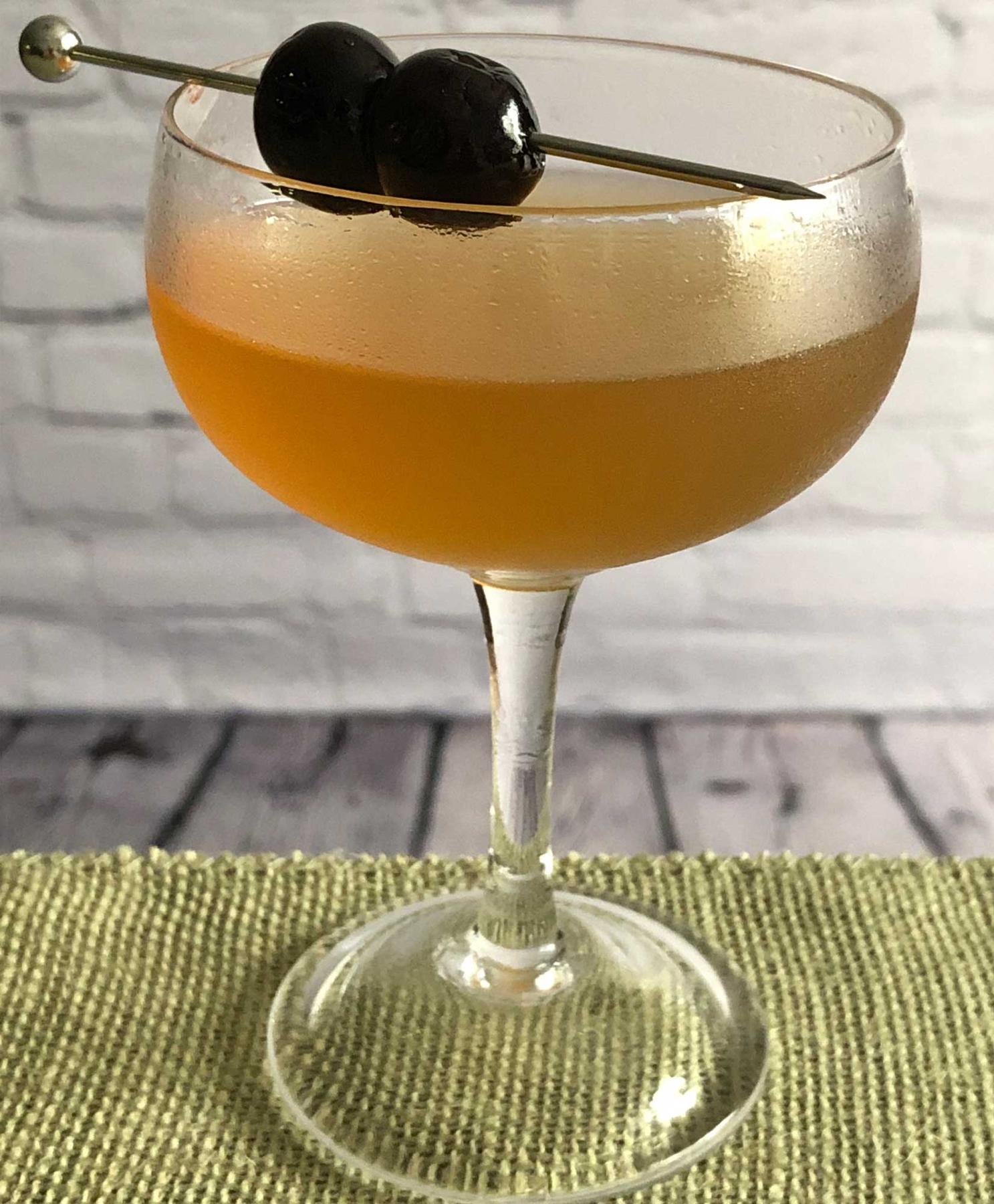 An example of the Core Reviver, the mixed drink (drink) featuring blended scotch whisky, Mattei Cap Corse Rouge Quinquina, Rothman & Winter Orchard Peach Liqueur, lemon juice, and maraschino cherry; photo by Lee Edwards