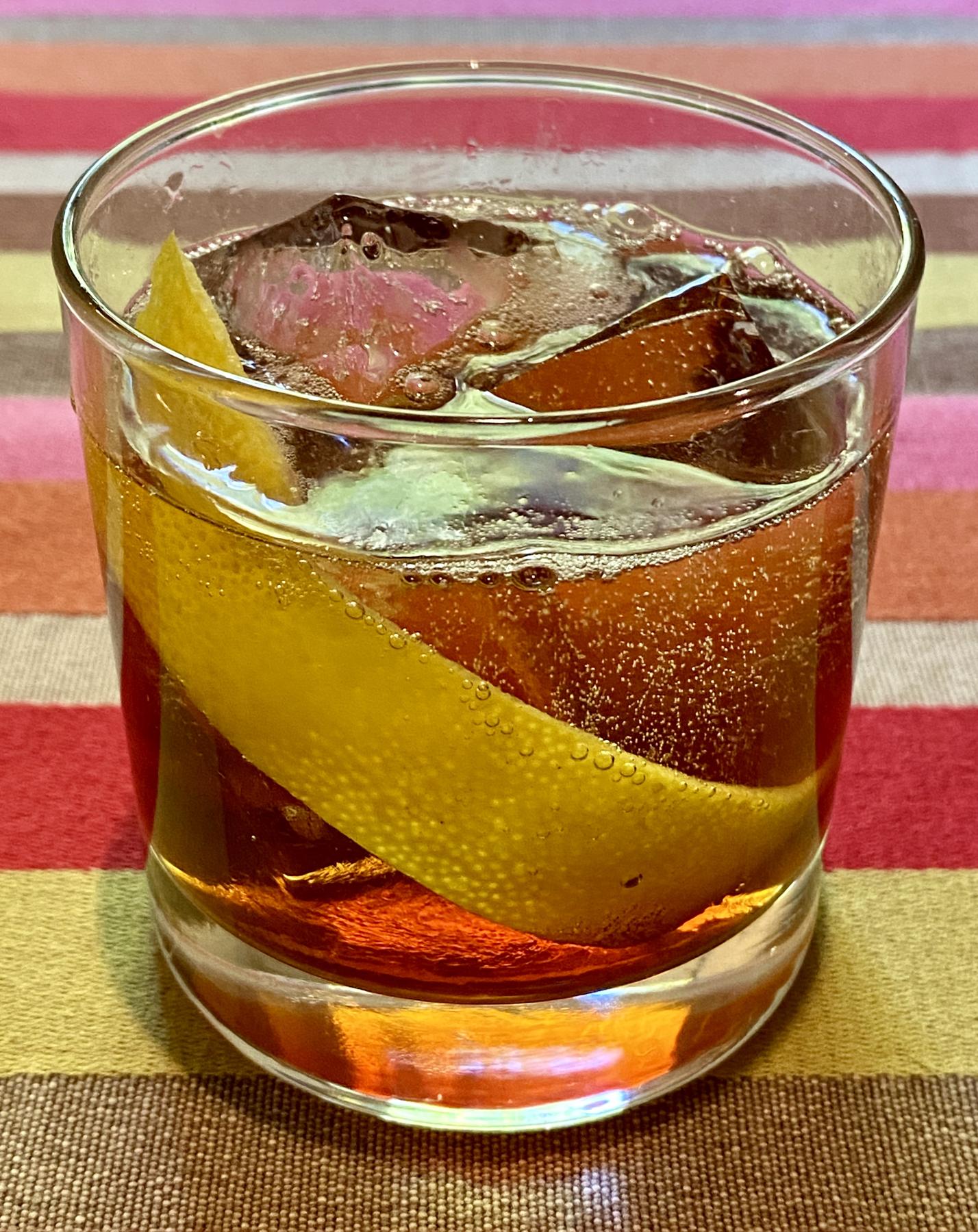 An example of the Mattei Rouge Spritz, the mixed drink (drink) featuring Mattei Cap Corse Rouge Quinquina, soda water, and grapefruit twist; photo by Martin Doudoroff