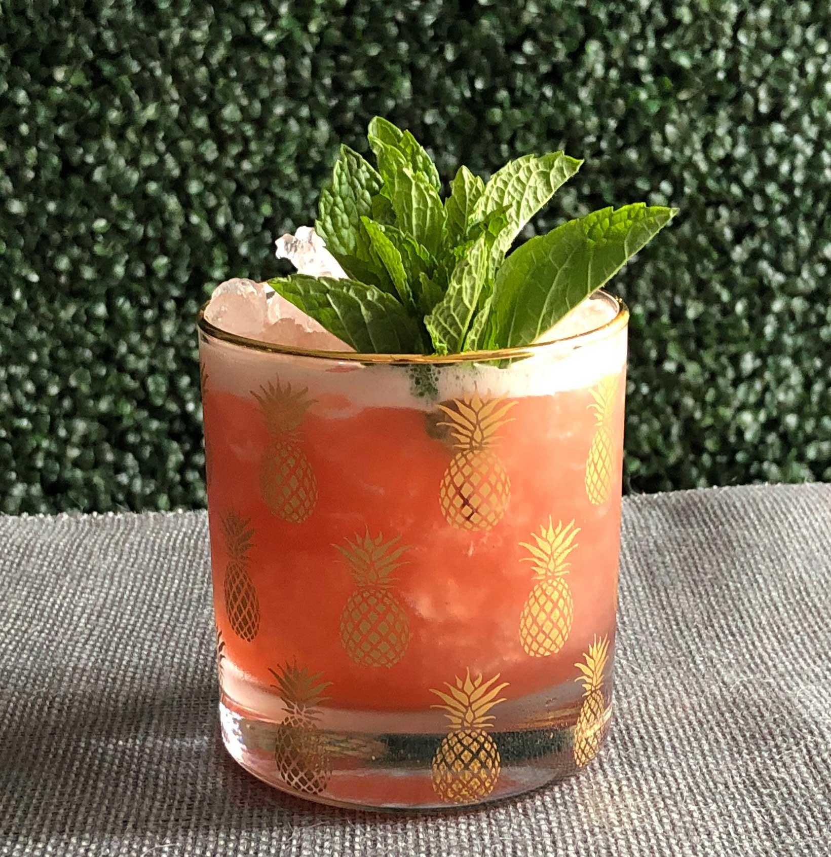 An example of the Jungle Boogie, the mixed drink (drink), by Cali Gold, Beretta, San Francisco, featuring Zirbenz Stone Pine Liqueur of the Alps, lime juice, grapefruit juice, cinnamon-infused sugar syrup, crushed ice, and sprig of mint; photo by Lee Edwards