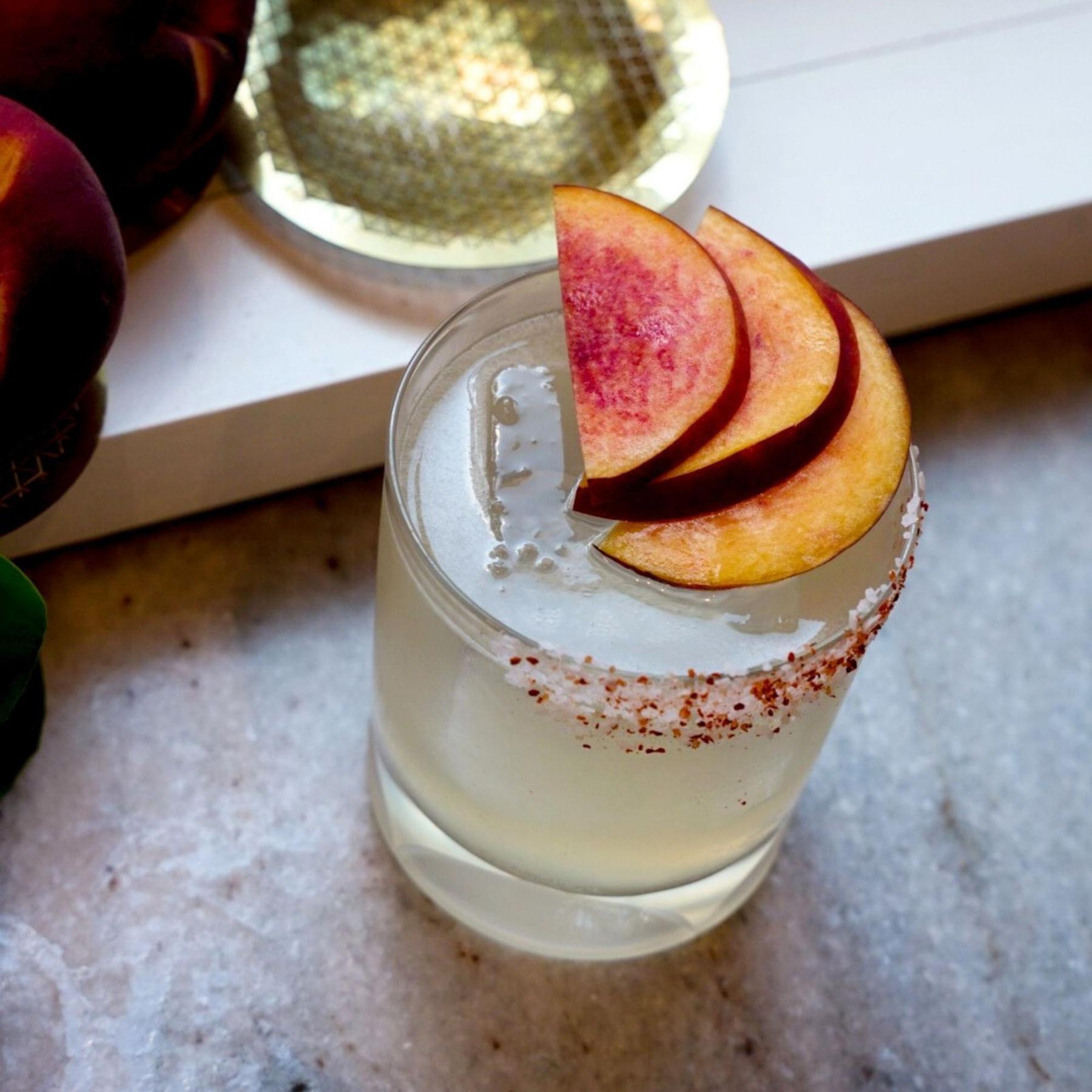 An example of the Ultimate Peach Margarita, the mixed drink (drink) featuring blanco tequila, Rothman & Winter Orchard Peach Liqueur, lime juice, salt, and peach slice; photo by Madison Young