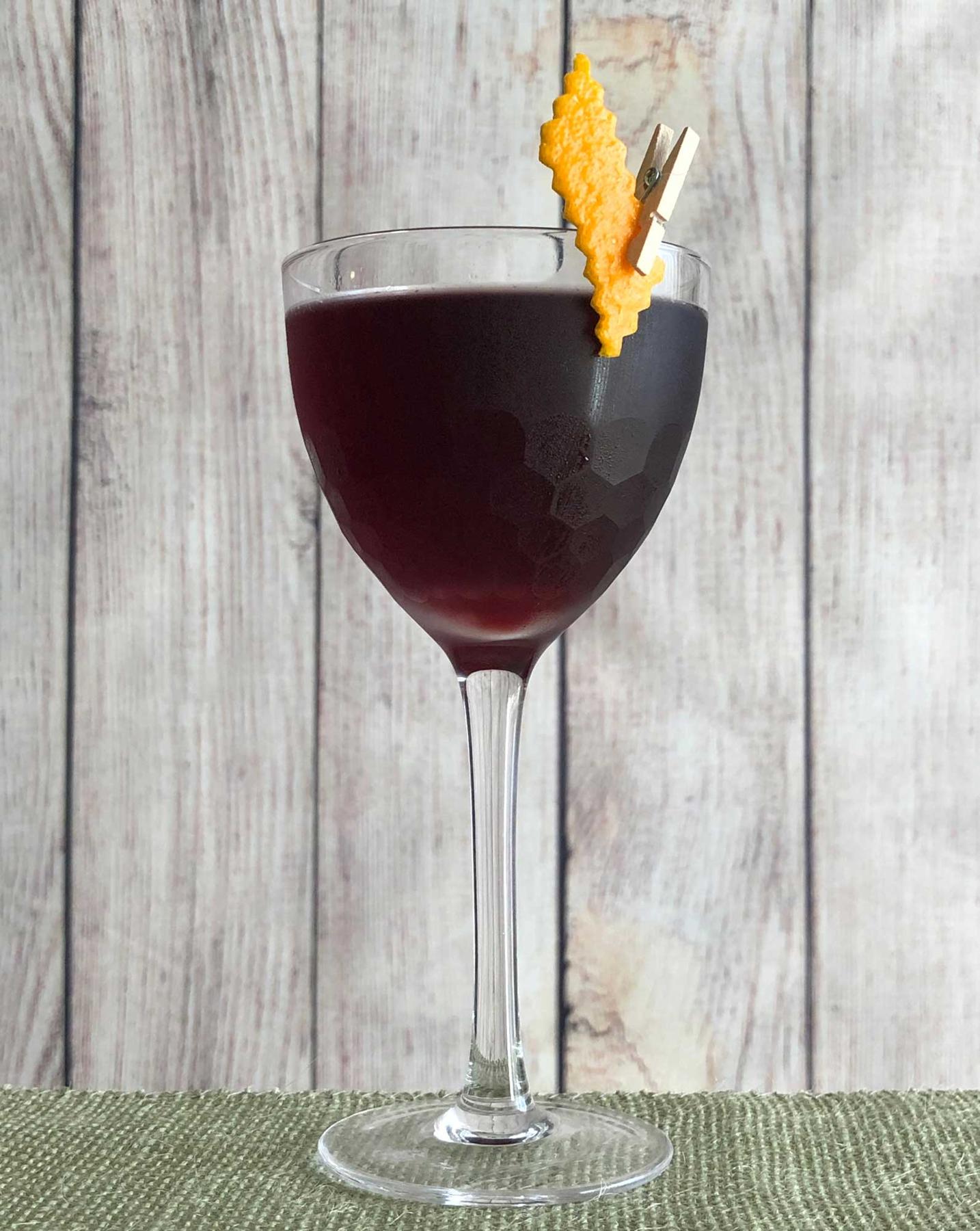An example of the Aunt Cathy’s Old Time Potion, the mixed drink (drink) featuring dry red wine, Averell Damson Plum Gin Liqueur, Campari, orange bitters, Fee Brothers Black Walnut Bitters, Fee Brothers Cardamom Bitters (Boker’s Style), and orange twist; photo by Lee Edwards