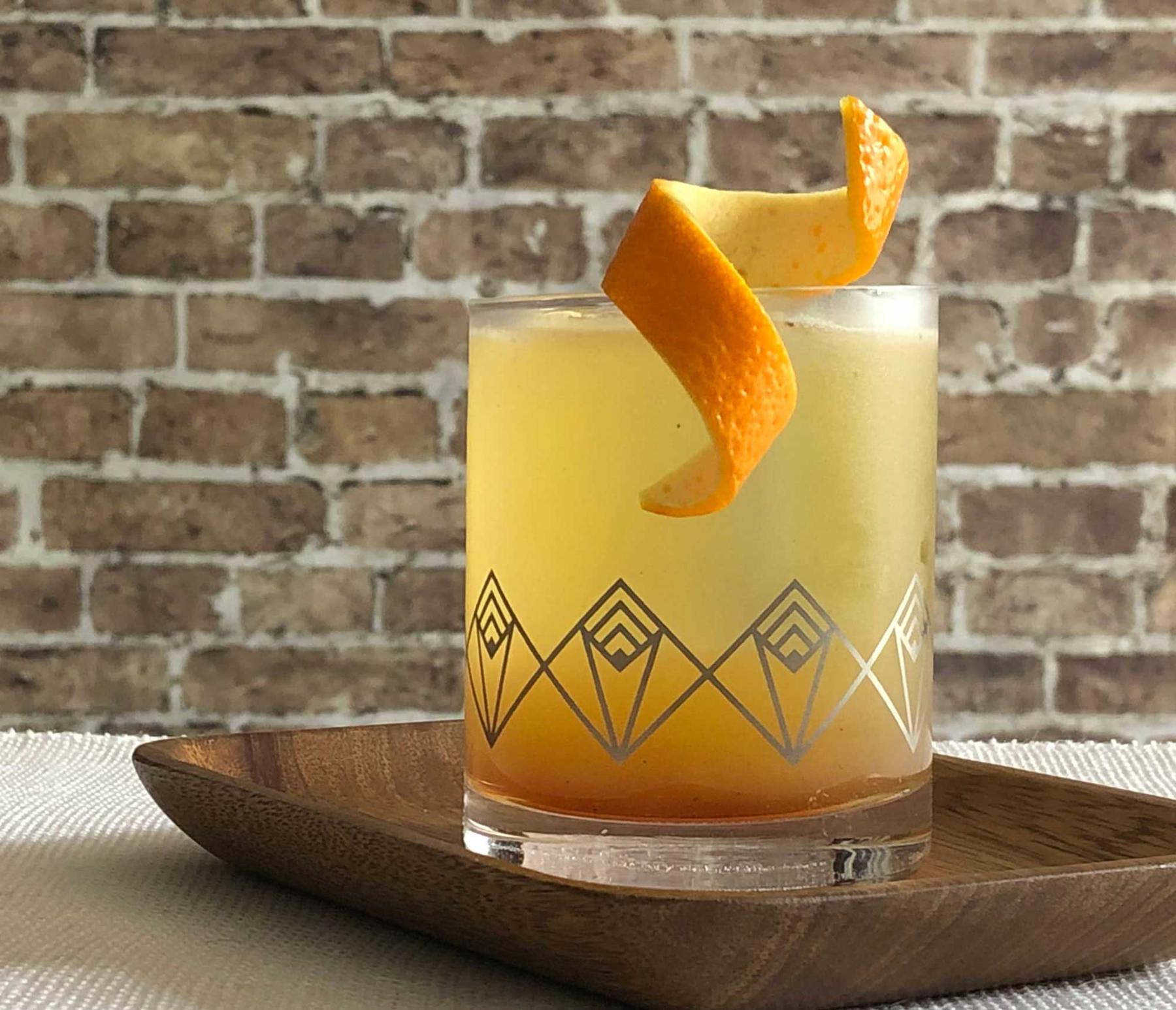 An example of the Prado 86, the mixed drink (drink), by Adam Hodak, Green Russell, Denver, featuring mezcal, orange-flavored liqueur, pineapple juice, orange juice, black pepper-infused simple syrup, and orange twist; photo by Lee Edwards