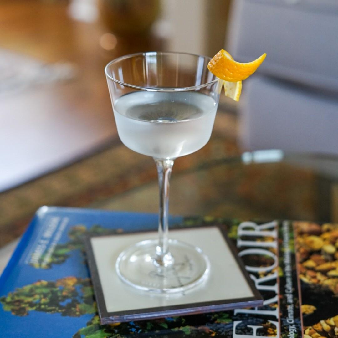 An example of the Blanc Martinez, the mixed drink (drink) featuring Hayman’s Old Tom Gin, Comoz Blanc Vermouth de Chambèry, Etter Kirsch, orange bitters, and orange twist