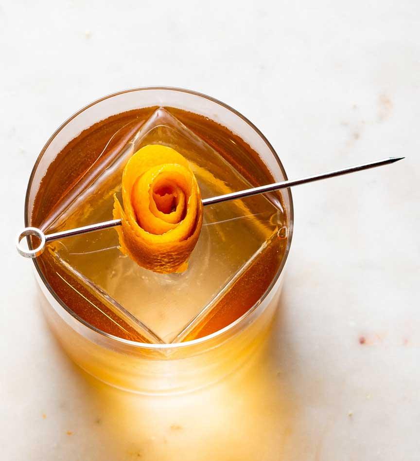 An example of the Alpine Old-Fashioned, the mixed drink (drink) featuring rye whiskey, Zirbenz Stone Pine Liqueur of the Alps, Dolin Génépy le Chamois Liqueur, simple syrup, and orange twist; photo by Mitchell Kim