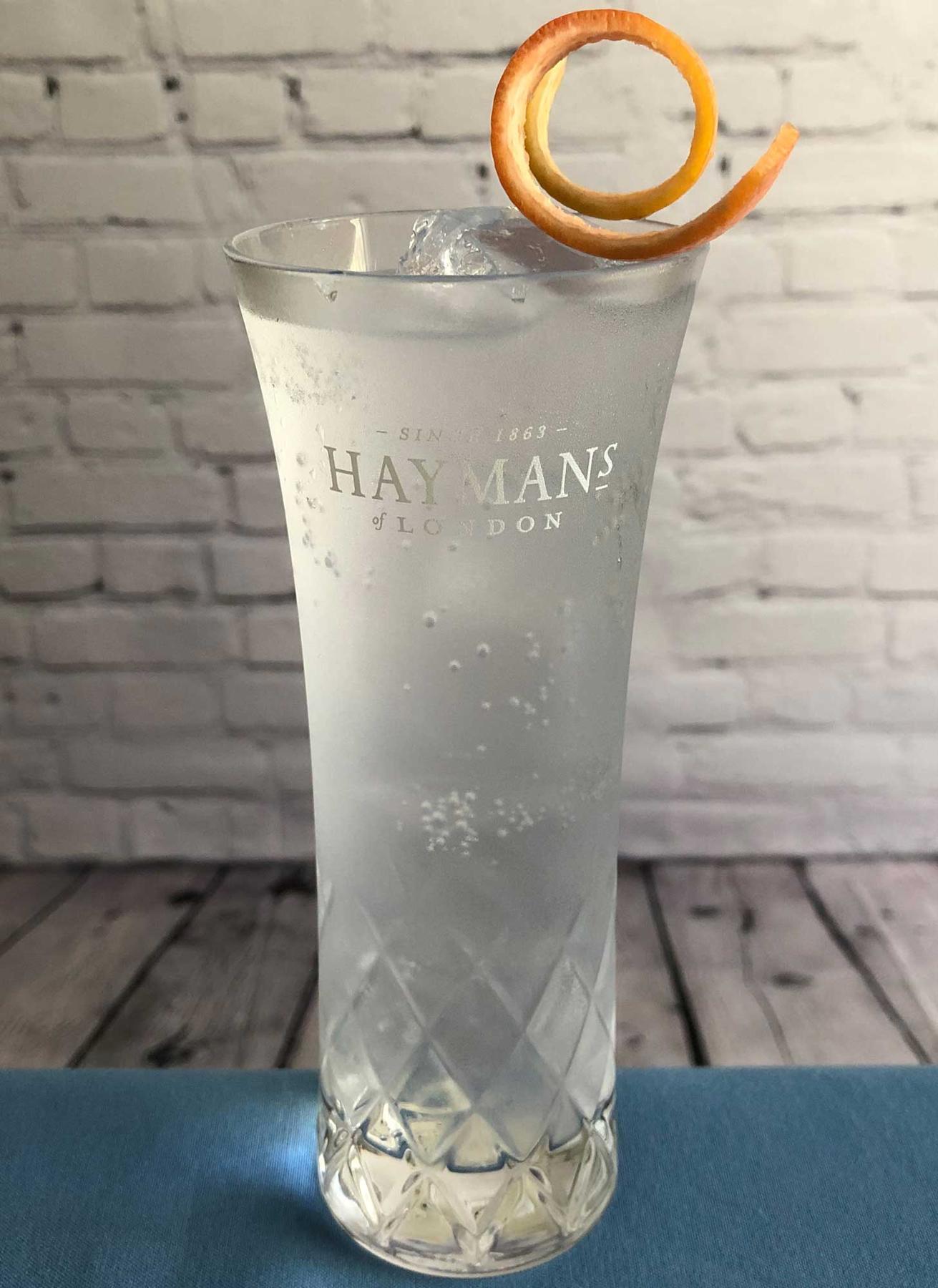 An example of the Royal Gin & Tonic, the mixed drink (drink) featuring Fever Tree Indian Tonic Water, Hayman’s Royal Dock Navy Strength Gin, lime wedge, and grapefruit twist; photo by Lee Edwards