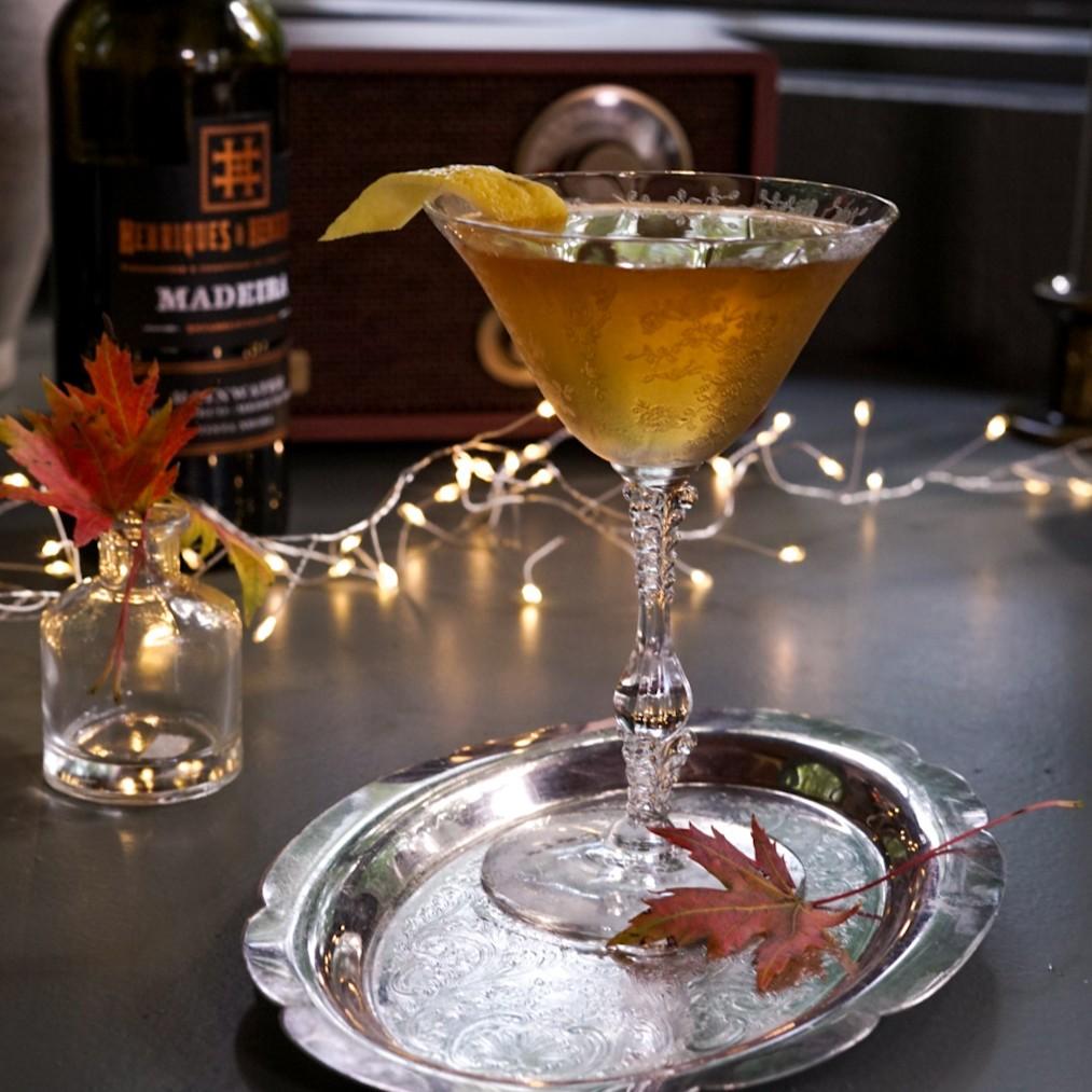An example of the Pheasant Pursuit, the mixed drink (drink) featuring Henriques & Henriques Rainwater Madeira, Hayman’s London Dry Gin, islay single malt scotch, and lemon twist; photo by Madison Young