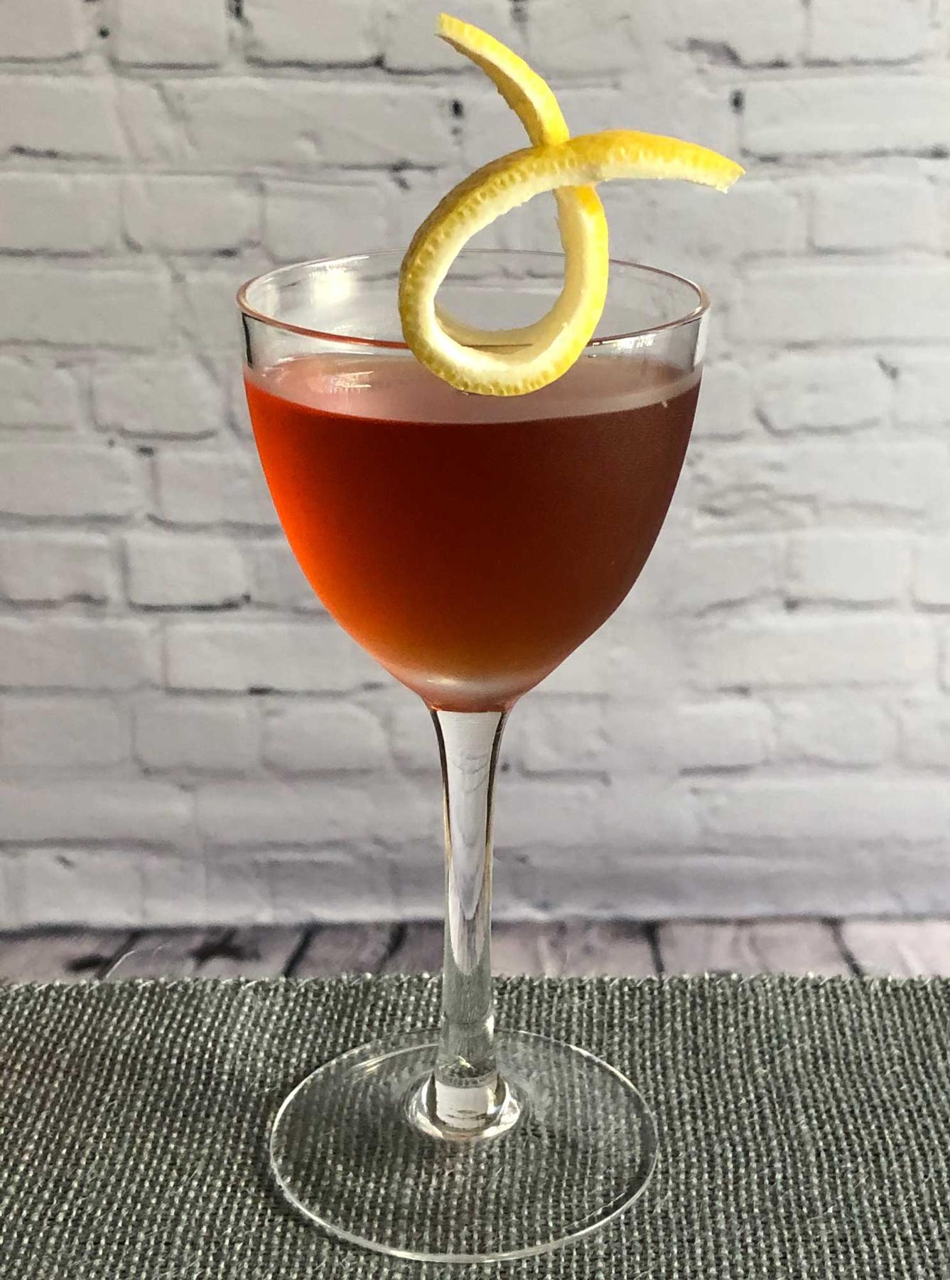 An example of the Moll Cocktail, the mixed drink (drink), by Savoy Cocktail Book, featuring Hayman’s Sloe Gin, Hayman’s London Dry Gin, Dolin Dry Vermouth de Chambéry, orange bitters, and lemon twist; photo by Lee Edwards