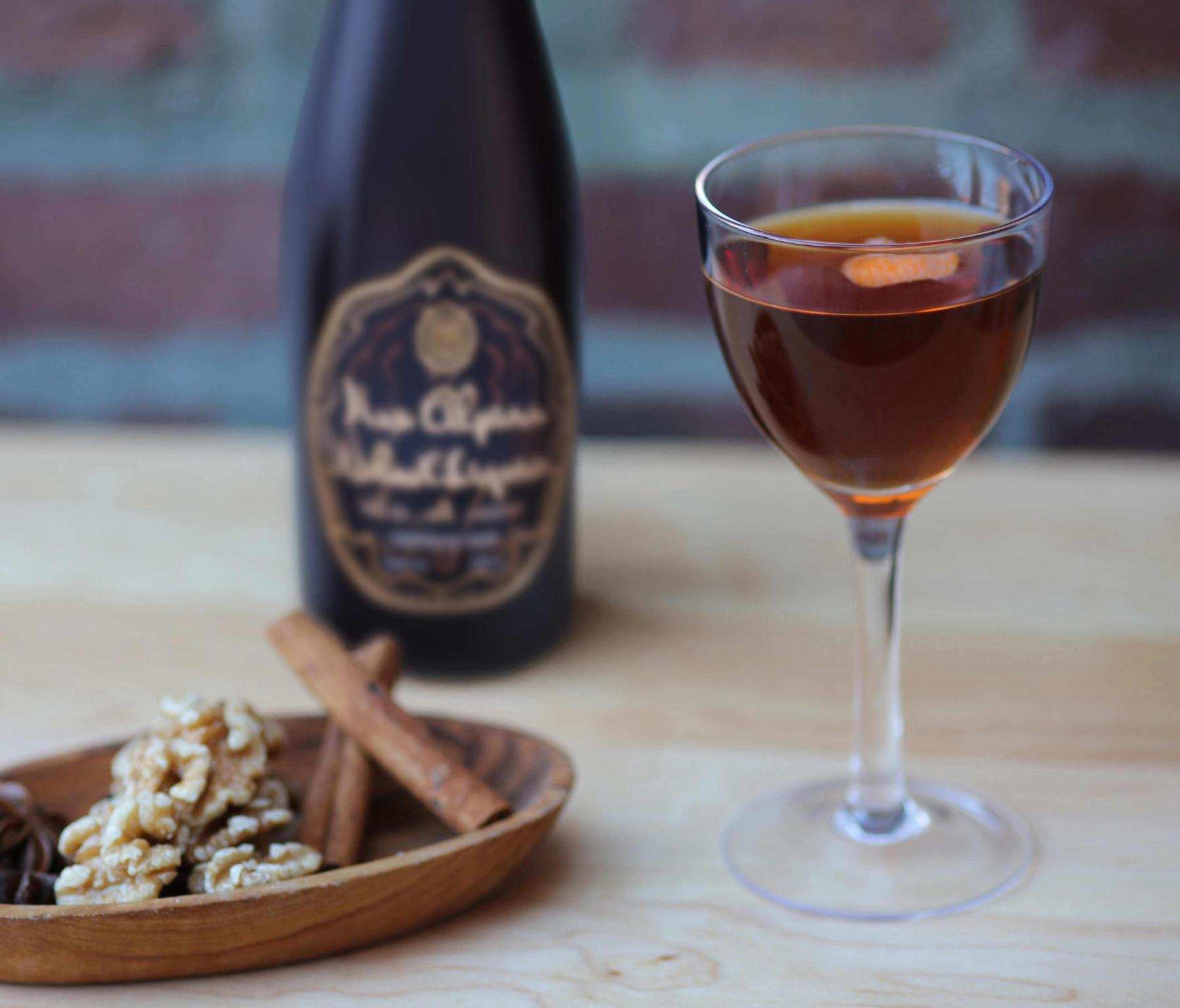 An example of the Black Manhattan, the mixed drink (drink) featuring rye whiskey, Cocchi Vermouth di Torino ‘Storico’, Nux Alpina Walnut Liqueur, and orange twist; photo by Lauren Clark