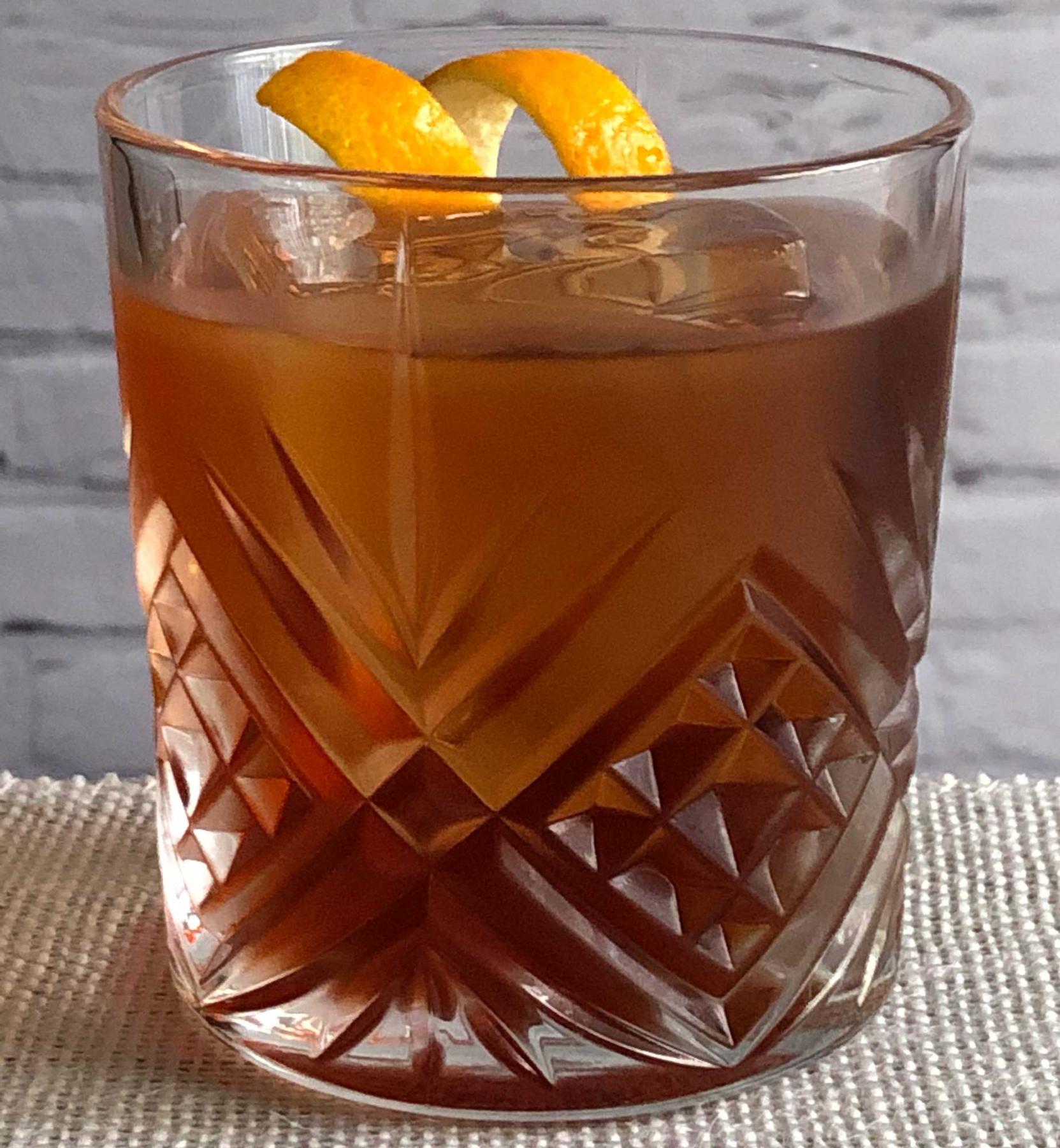 An example of the Petit Boulevardier, the mixed drink (drink) featuring Cardamaro Vino Amaro, Dolin Rouge Vermouth de Chambéry, Aperitivo Cappelletti, and orange twist; photo by Lee Edwards
