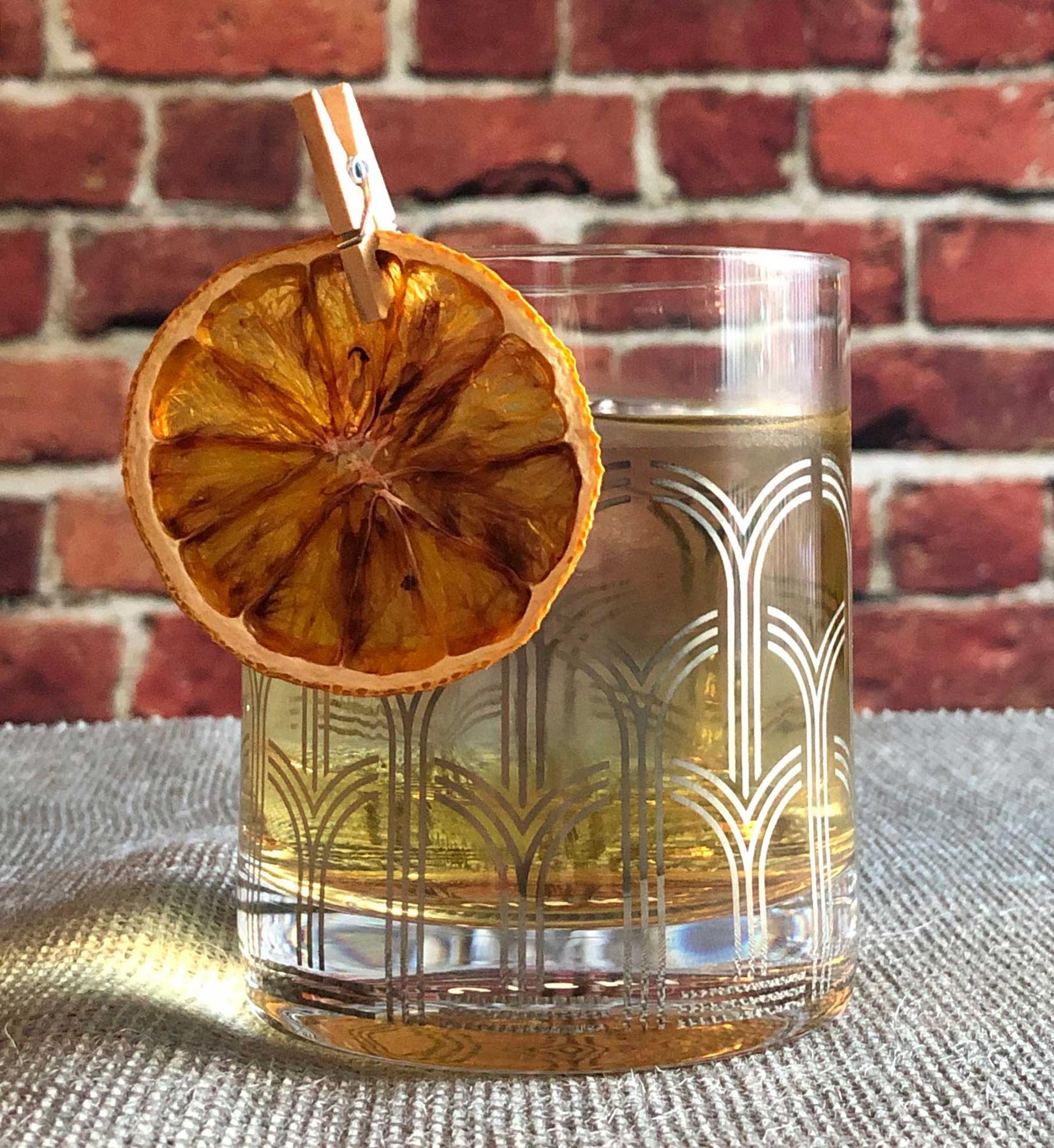 An example of the Charlotte Gainsbourg, the mixed drink (drink), by Kelley Swenson, Portland, Oregon, from the book “Left Coast Libations”, featuring Cocchi Americano Bianco, orange-flavored liqueur, pastis, and orange wheel; photo by Lee Edwards