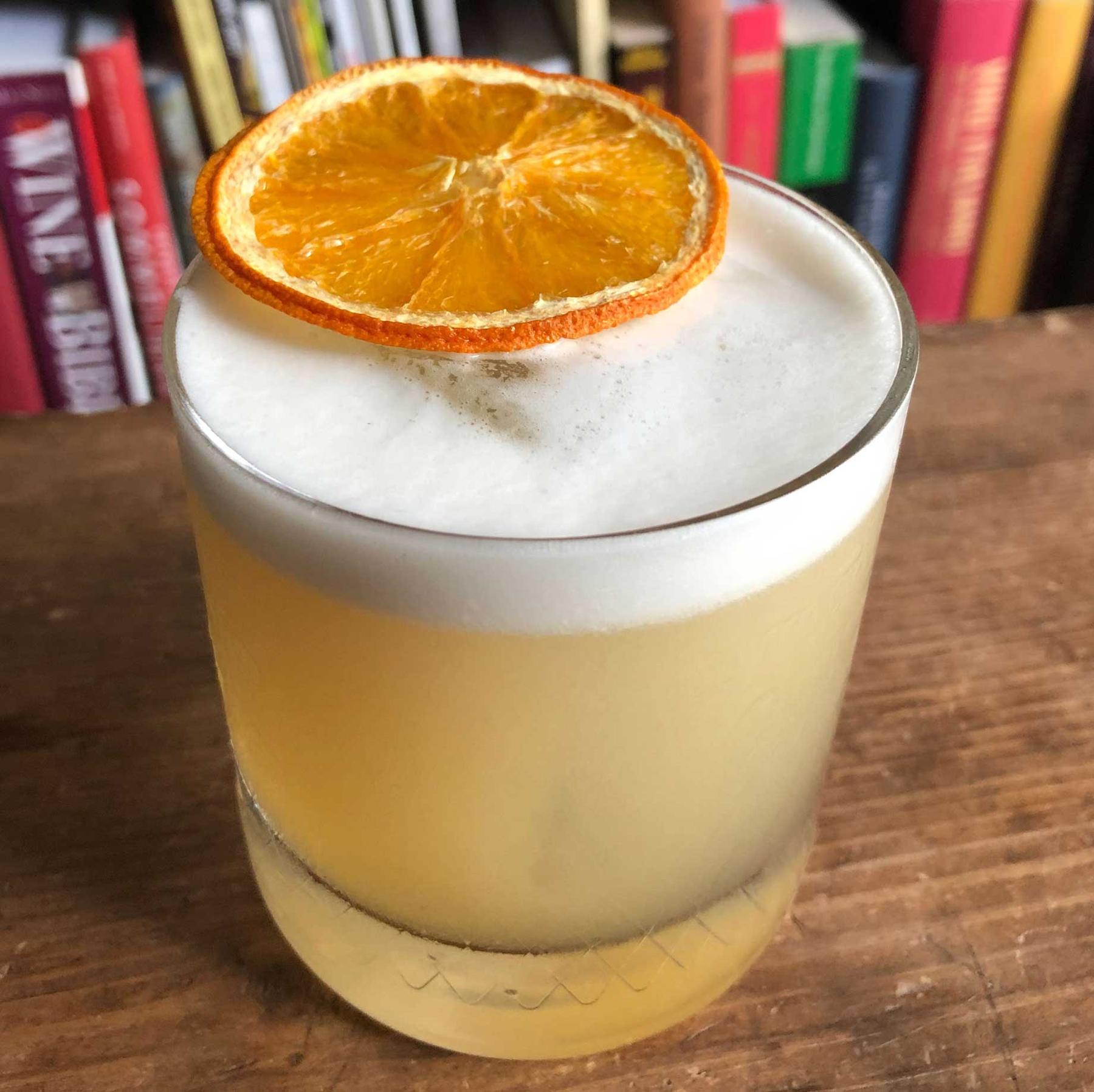An example of the Peach Whiskey Sour, the mixed drink (drink) featuring bourbon whiskey, Rothman & Winter Orchard Peach Liqueur, egg white, lemon juice, simple syrup, and orange twist; photo by Lee Edwards