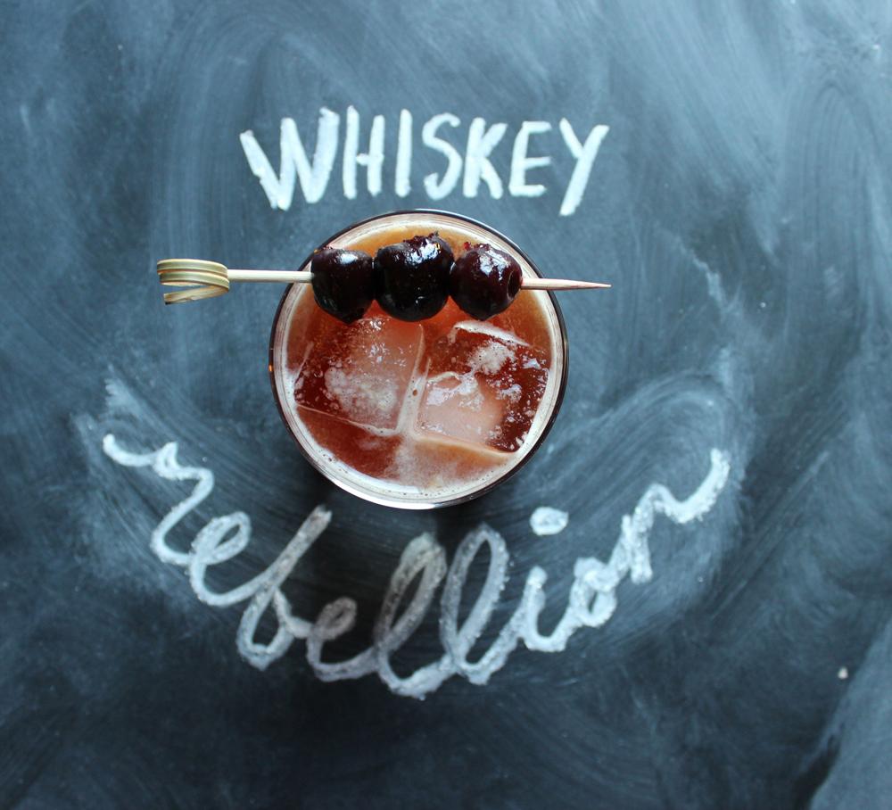 An example of the Whiskey Rebellion, the mixed drink (drink), by Brittany Bradley, South on Main, Little Rock, Arkansas, featuring Rothman & Winter Orchard Cherry Liqueur, rye whiskey, Cocchi Vermouth di Torino ‘Storico’, orange juice, and maraschino cherry; photo by Brittany Bradley