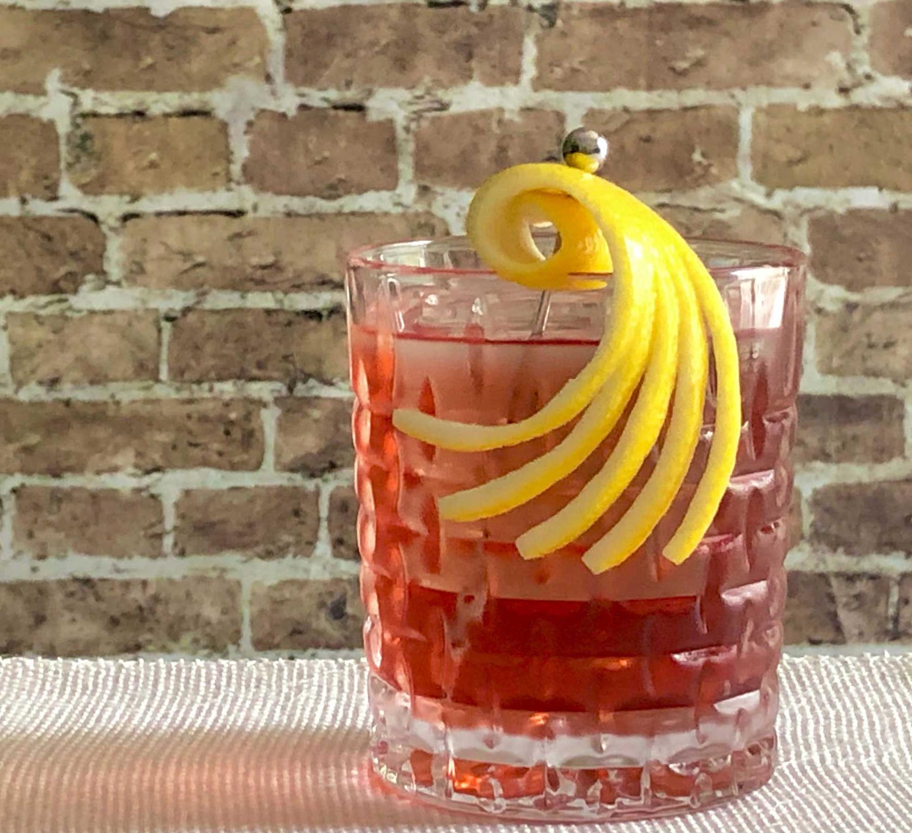 An example of the Hidden Roots, the mixed drink (drink) featuring bourbon whiskey, Cocchi Americano Rosa, and lemon twist; photo by Lee Edwards