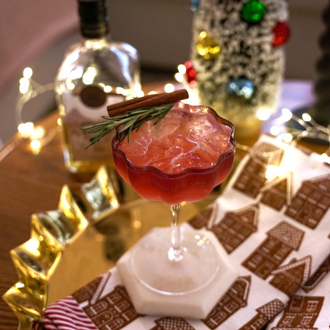 An example of the Sally's Holiday Spritz, the mixed drink (drink), by Craft & Commerce, San Diego, CA, featuring rosé, Meunier Génépy ‘Altitude’ Liqueur, reposado tequila, cranberry syrup, lemon juice, sprig of rosemary, and cinnamon stick; photo by Madison Young
