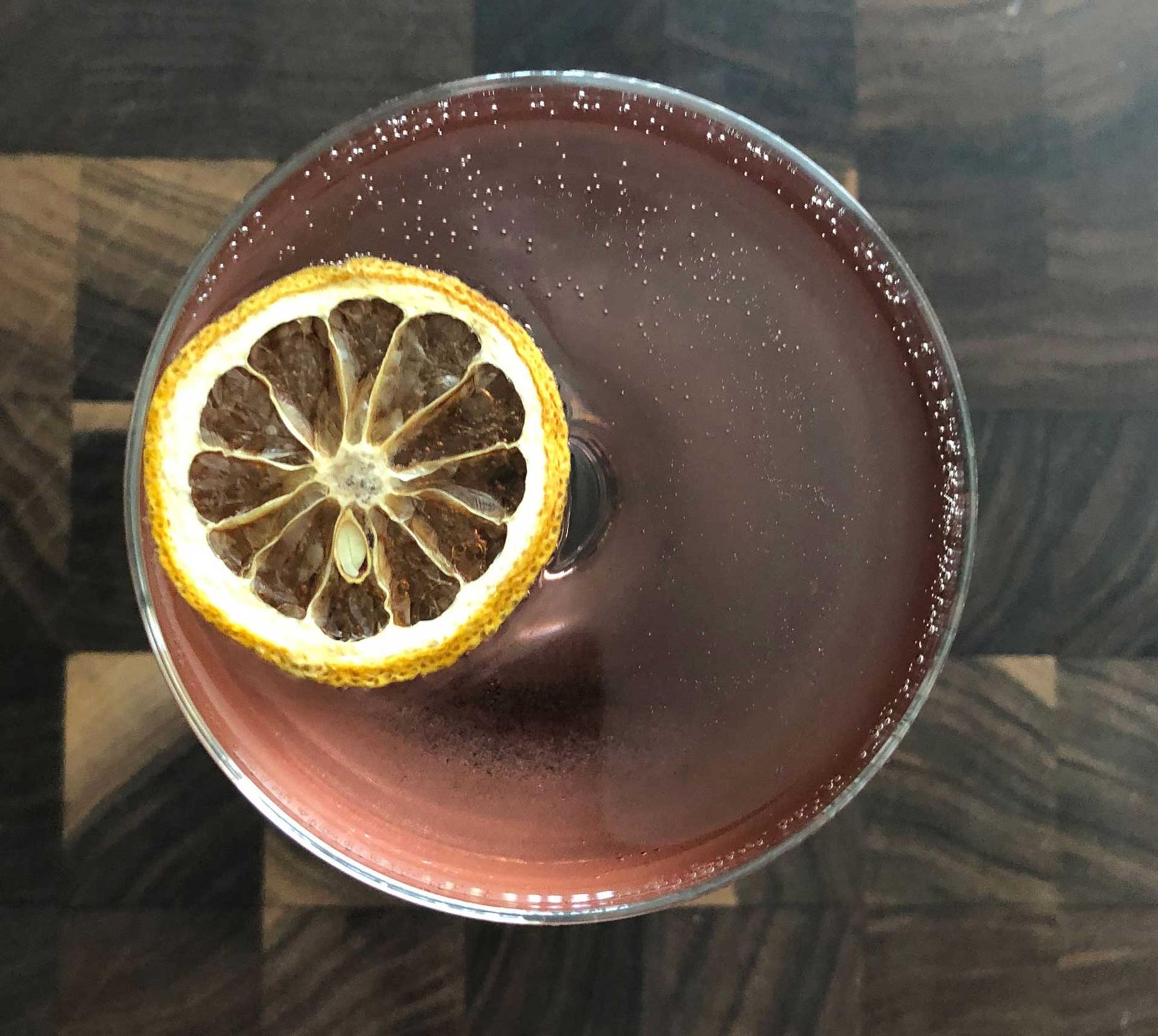 An example of the Prairie Pooch, the mixed drink (drink) featuring Hayman’s London Dry Gin, Cocchi Americano Rosa, Dolin Blanc Vermouth de Chambéry, sparkling wine, Rothman & Winter Crème de Violette, and lemon twist; photo by Lee Edwards