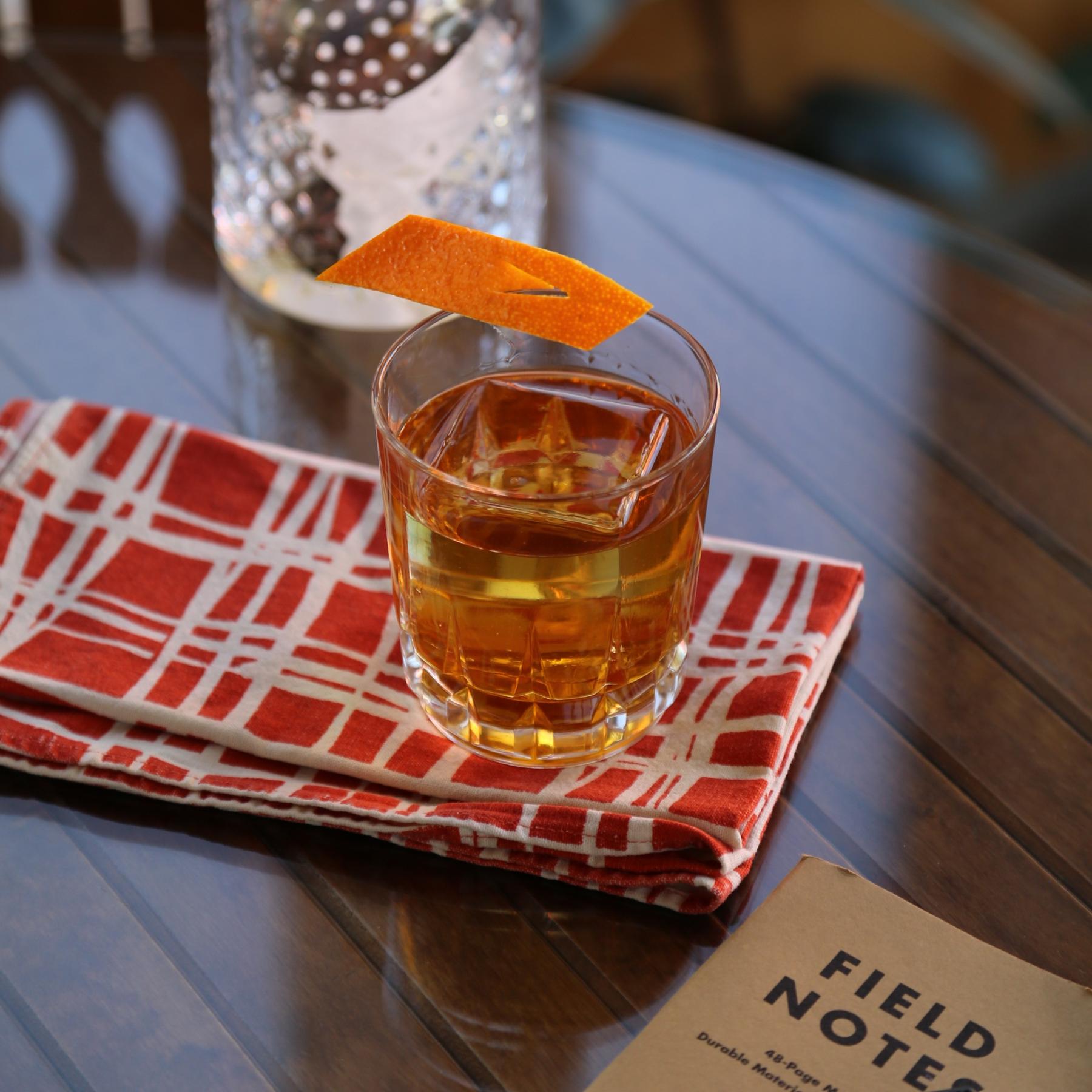 An example of the Rusty Nils, the mixed drink (drink) featuring bourbon whiskey, KRONAN Swedish Punsch, and orange twist; photo by Megan Heinowski