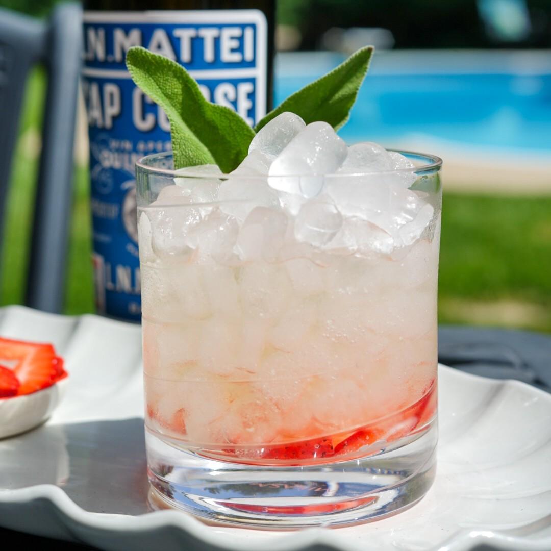 An example of the Portico Spritz, the mixed drink (drink), by Inspired by Kellie Thorn, featuring soda water, Mattei Cap Corse Blanc Quinquina, orange twist, and sprig of sage