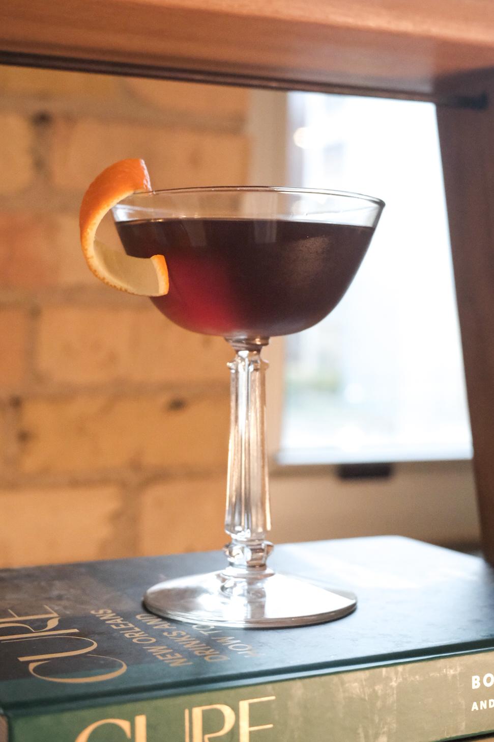 An example of the Timbal Manhattan, the mixed drink (drink) featuring rye whiskey, Timbal Vermut de Reus Sweet Red, orange bitters, and orange twist