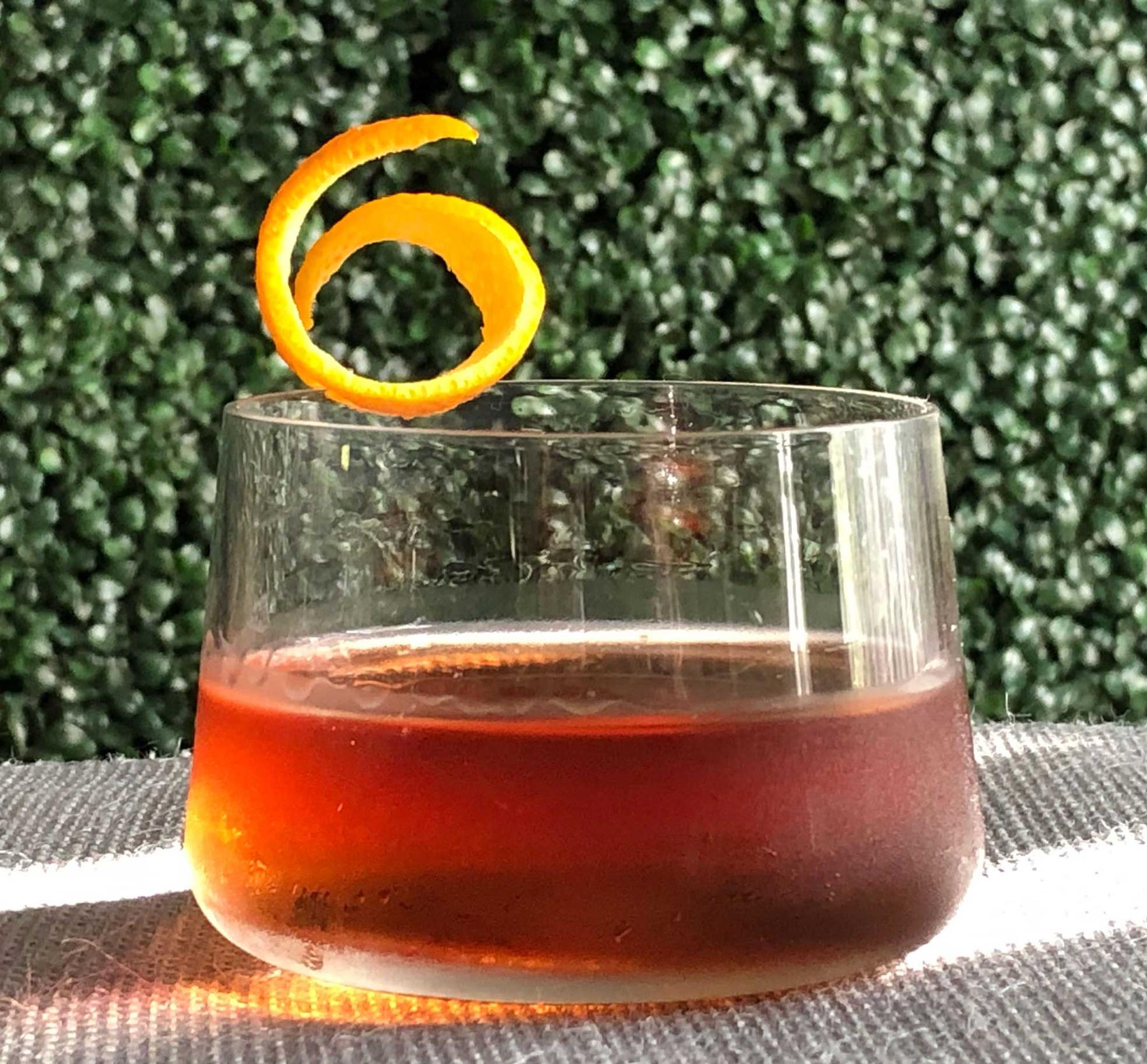 An example of the Pat’s Old Friend, the mixed drink (drink), adapted from the Pat’s Special, Savoy Cocktail Book, featuring Bonal Gentiane-Quina, Hayman’s Old Tom Gin, Mas Peyre Rancio Sec “Le Démon de Midi”, grenadine, Rothman & Winter Orchard Apricot Liqueur, and orange twist; photo by Lee Edwards