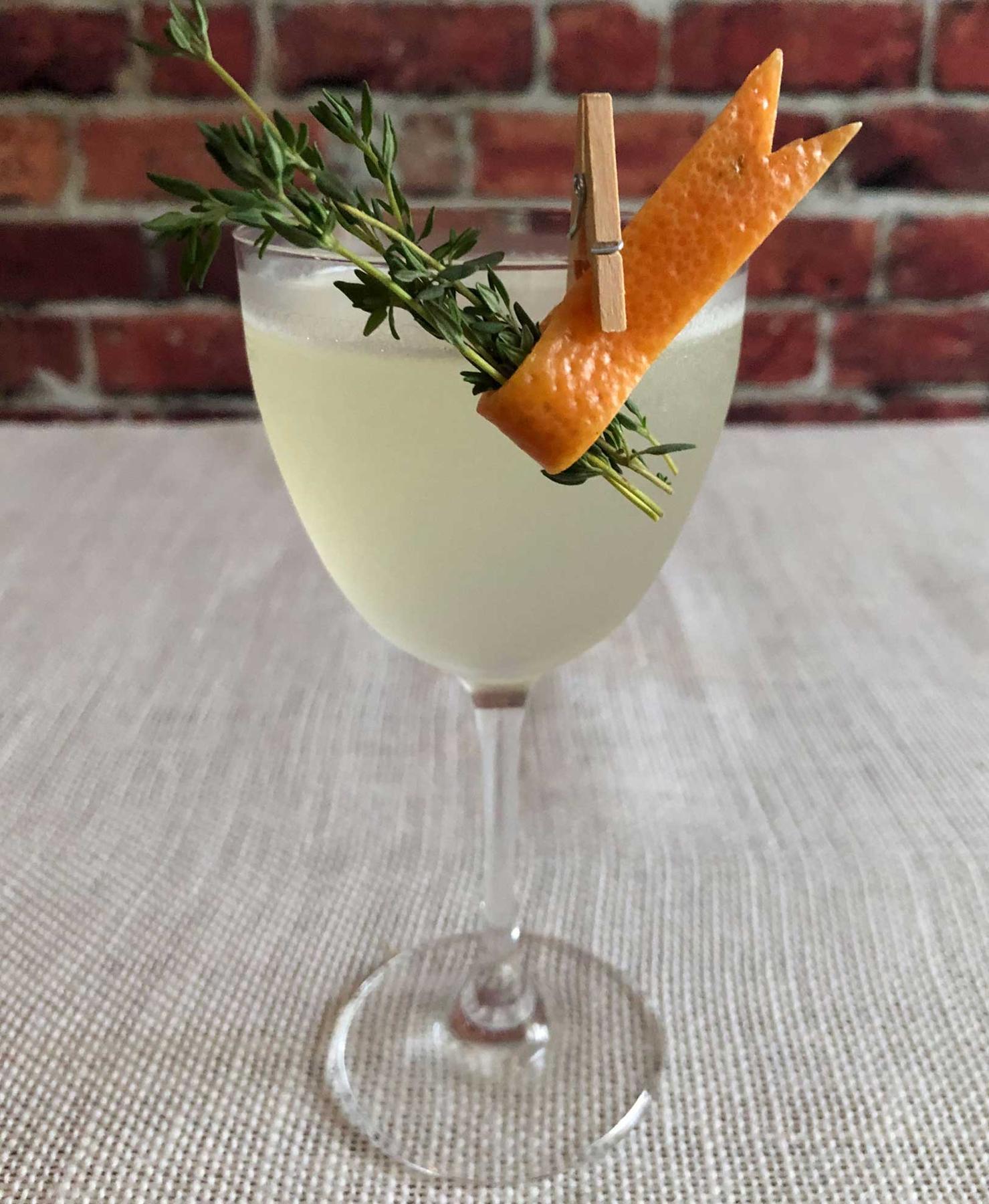 An example of the Hemingway in Europe, the mixed drink (drink), by Patrick Williams, Punch Bowl Social, Denver, featuring Batavia Arrack van Oosten, grapefruit oleo-saccharum, lime juice, maraschino liqueur, grapefruit twist, and sprig of thyme; photo by Lee Edwards