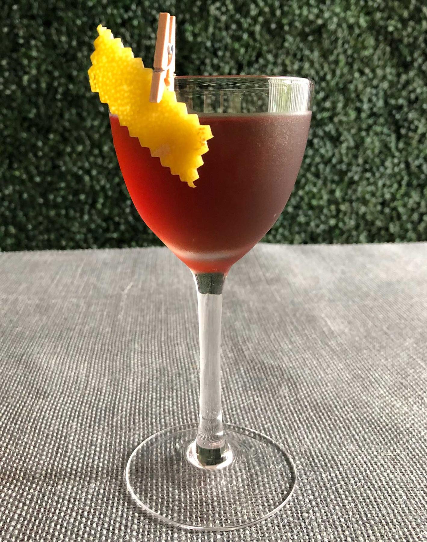 An example of the Purple Globe, the mixed drink (drink) featuring Hayman’s London Dry Gin, Averell Damson Plum Gin Liqueur, Pasubio Vino Amaro, and lemon twist; photo by Lee Edwards