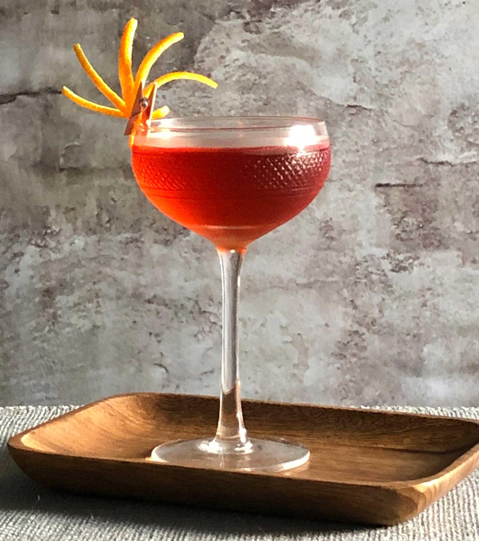 An example of the Negroni Rosa, the mixed drink (drink) featuring Hayman’s London Dry Gin, Cocchi Americano Rosa, Aperitivo Cappelletti, and orange twist; photo by Lee Edwards