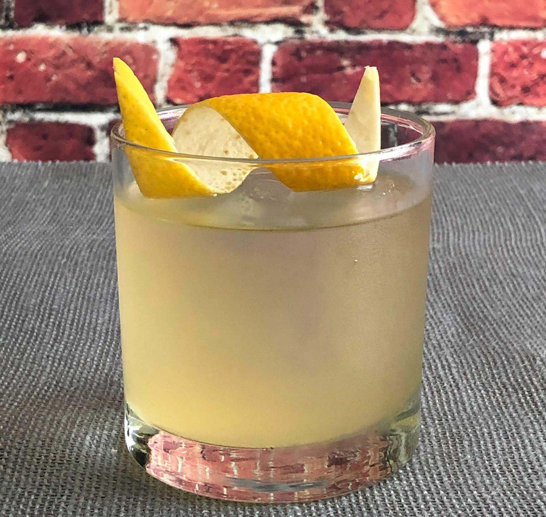 An example of the Little Corporal, the mixed drink (drink), by Andy Arrington, Victory Wine Group, Texas, featuring rhum agricole blanc, Mattei Cap Corse Blanc Quinquina, Amaro Alta Verde, large ice cube, and lemon twist; photo by Lee Edwards