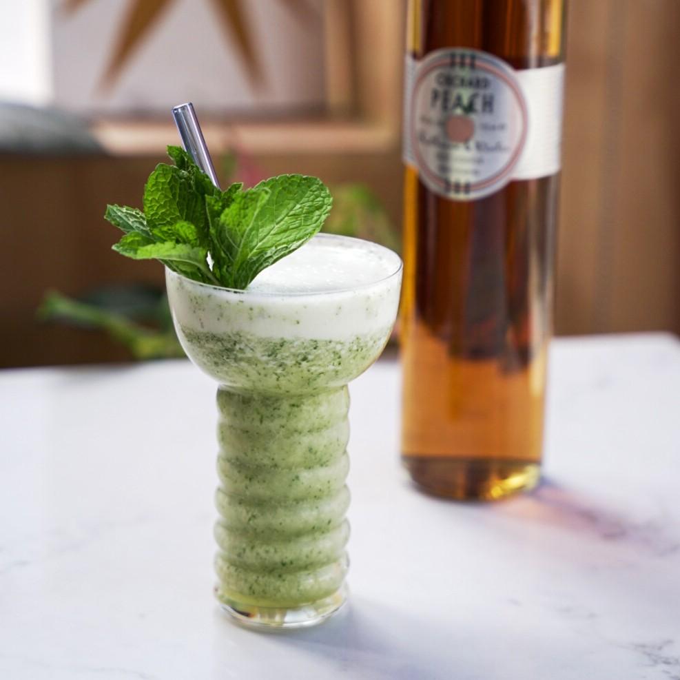 An example of the Missionary’s Downfall, the mixed drink (drink), by Don the Beachcomber, featuring light rum, honey syrup, Rothman & Winter Orchard Peach Liqueur, lime juice, mint leaf, crushed ice, pineapple cubes, and sprig of mint; photo by Madison Young
