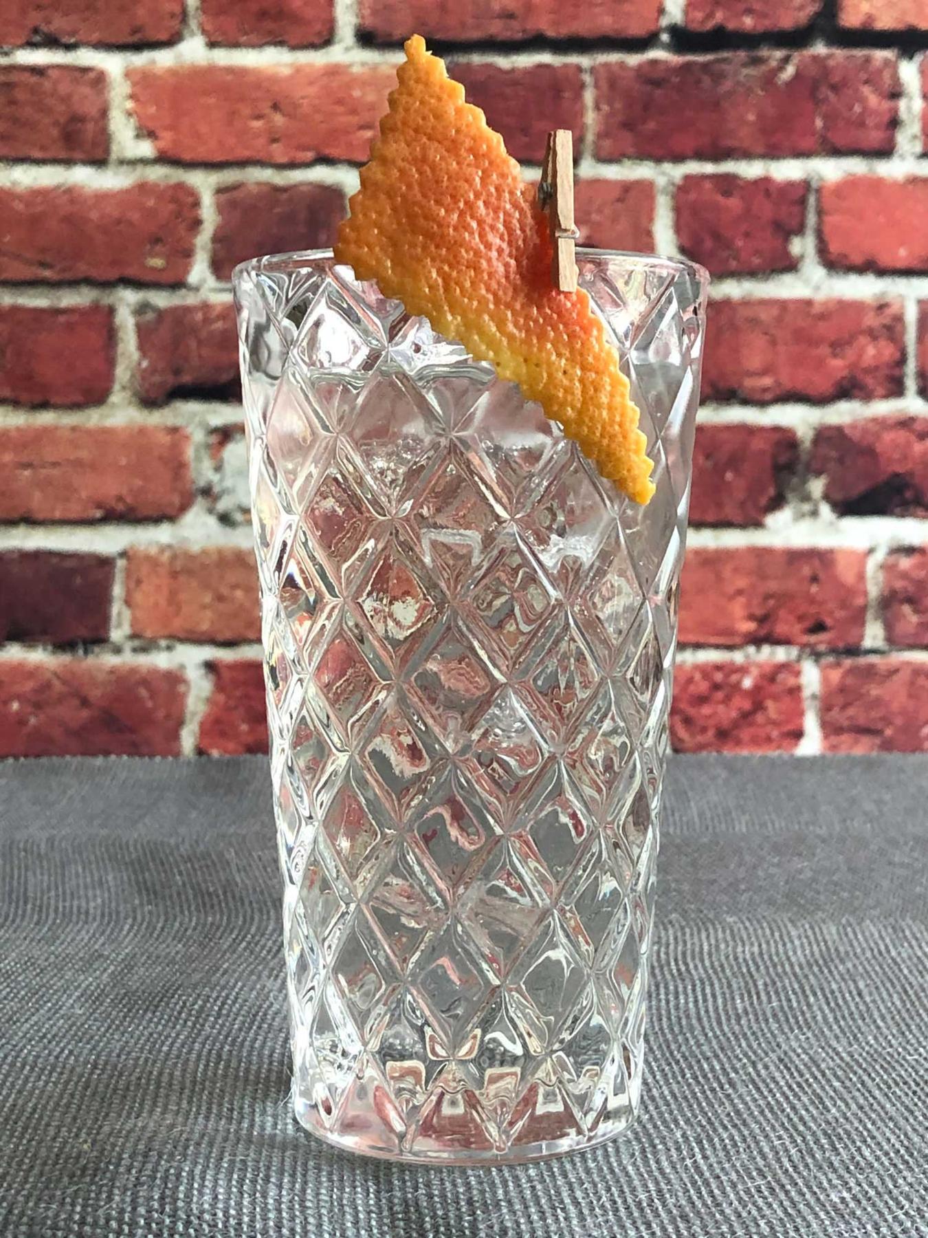 An example of the Clear and Present Highball, the mixed drink (drink) featuring soda water, Salers Gentian Apéritif, Dolin Blanc Vermouth de Chambéry, and grapefruit twist; photo by Lee Edwards