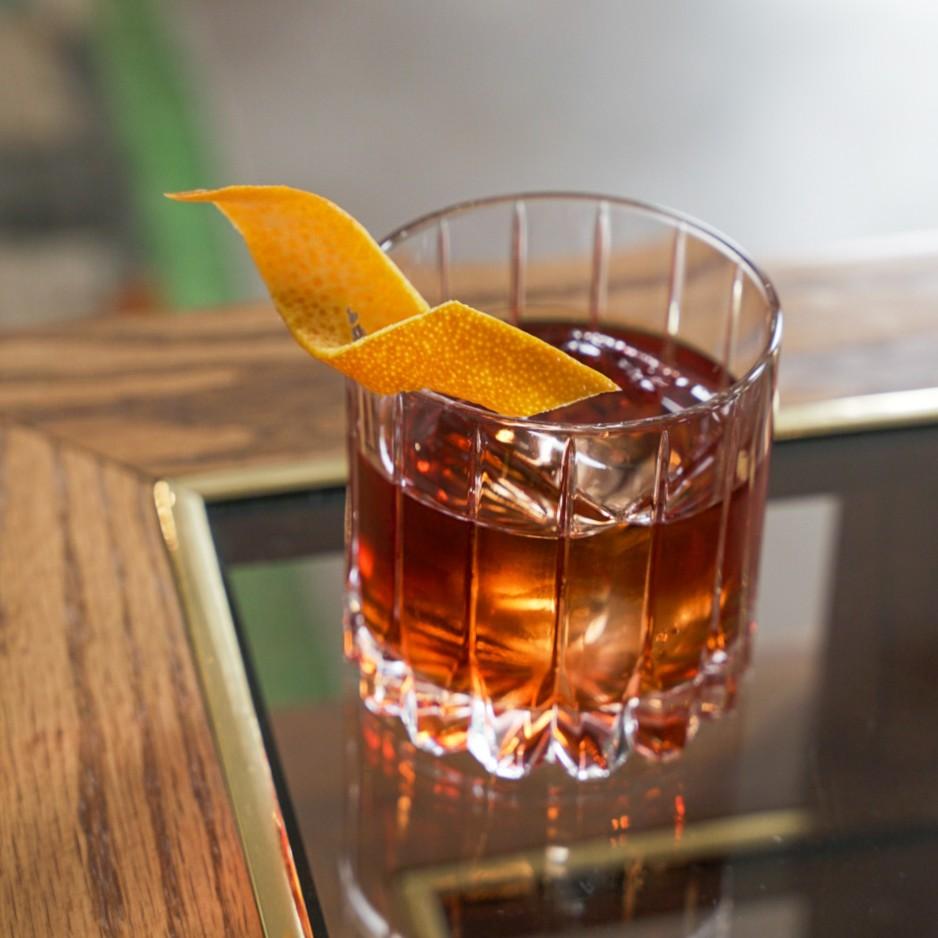 An example of the Negroni, the mixed drink (drink) featuring Hayman’s London Dry Gin, Aperitivo Mazzura, Timbal Vermut de Reus Sweet Red, and orange twist; photo by Madison Young