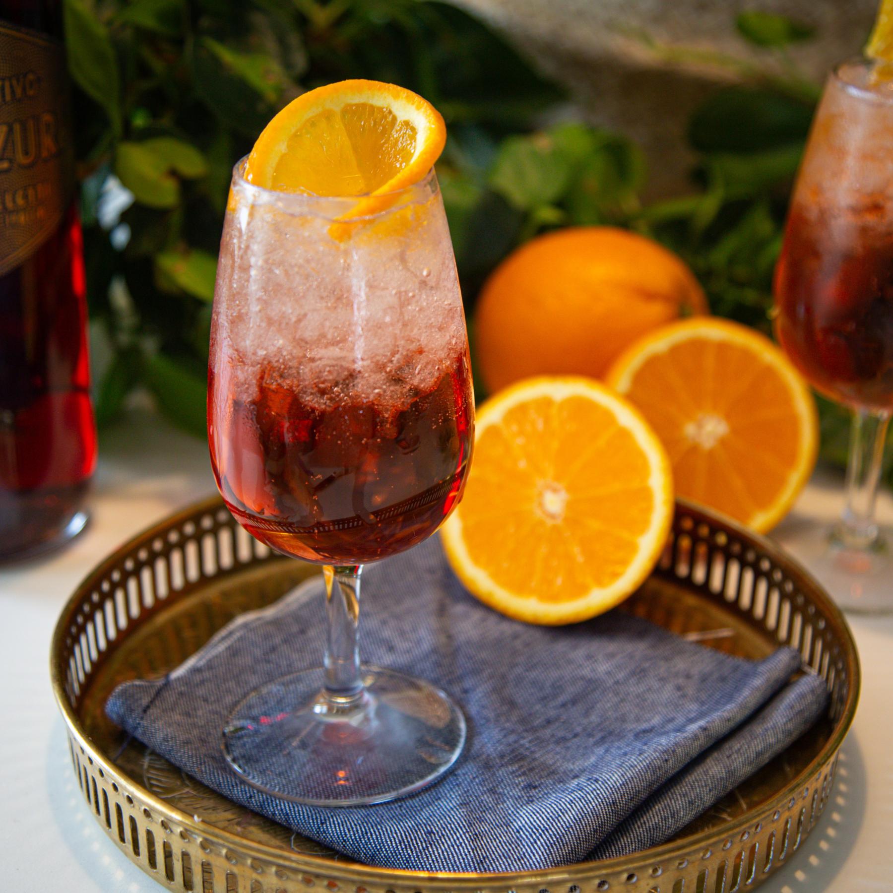 An example of the Bicicletta, the mixed drink (drink) featuring dry white wine, Aperitivo Mazzura, soda water, and orange wheel; photo by Megan Heinowski