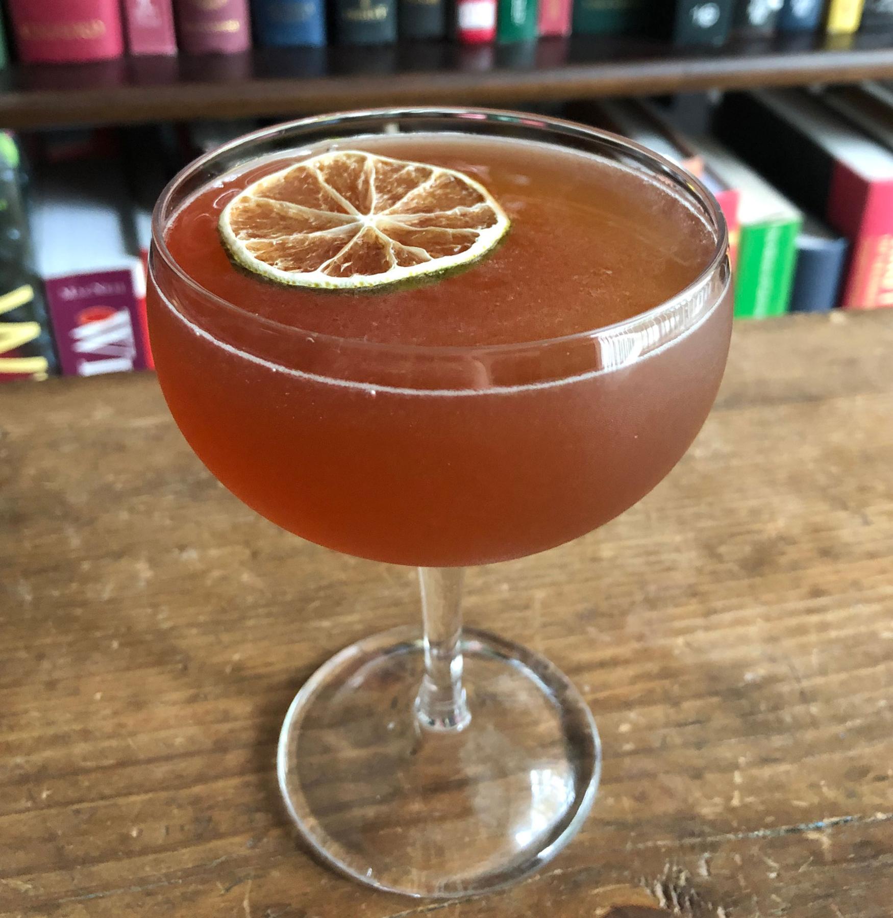 An example of the Millionaire No. 1, the mixed drink (drink), by Savoy Cocktail Book, featuring Hayman’s Sloe Gin, Smith & Cross Traditional Jamaica Rum, Blume Marillen Apricot Eau-de-Vie, lime juice, grenadine, rich simple syrup, and lime wheel; photo by Lee Edwards