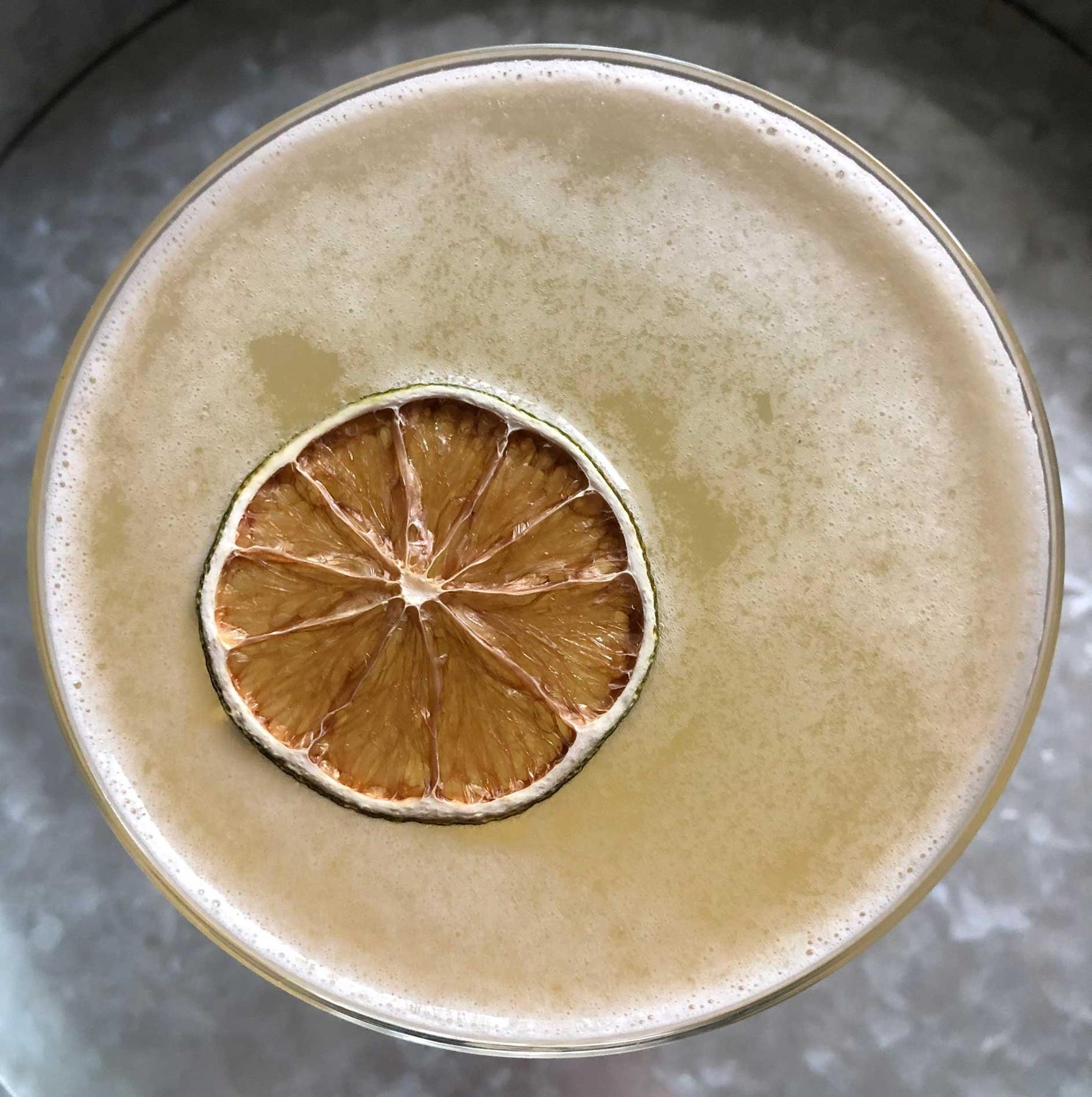 An example of the Airmail, the mixed drink (drink) featuring sparkling wine, Batavia Arrack van Oosten, lime juice, rich demerara syrup, and lime wheel; photo by Lee Edwards