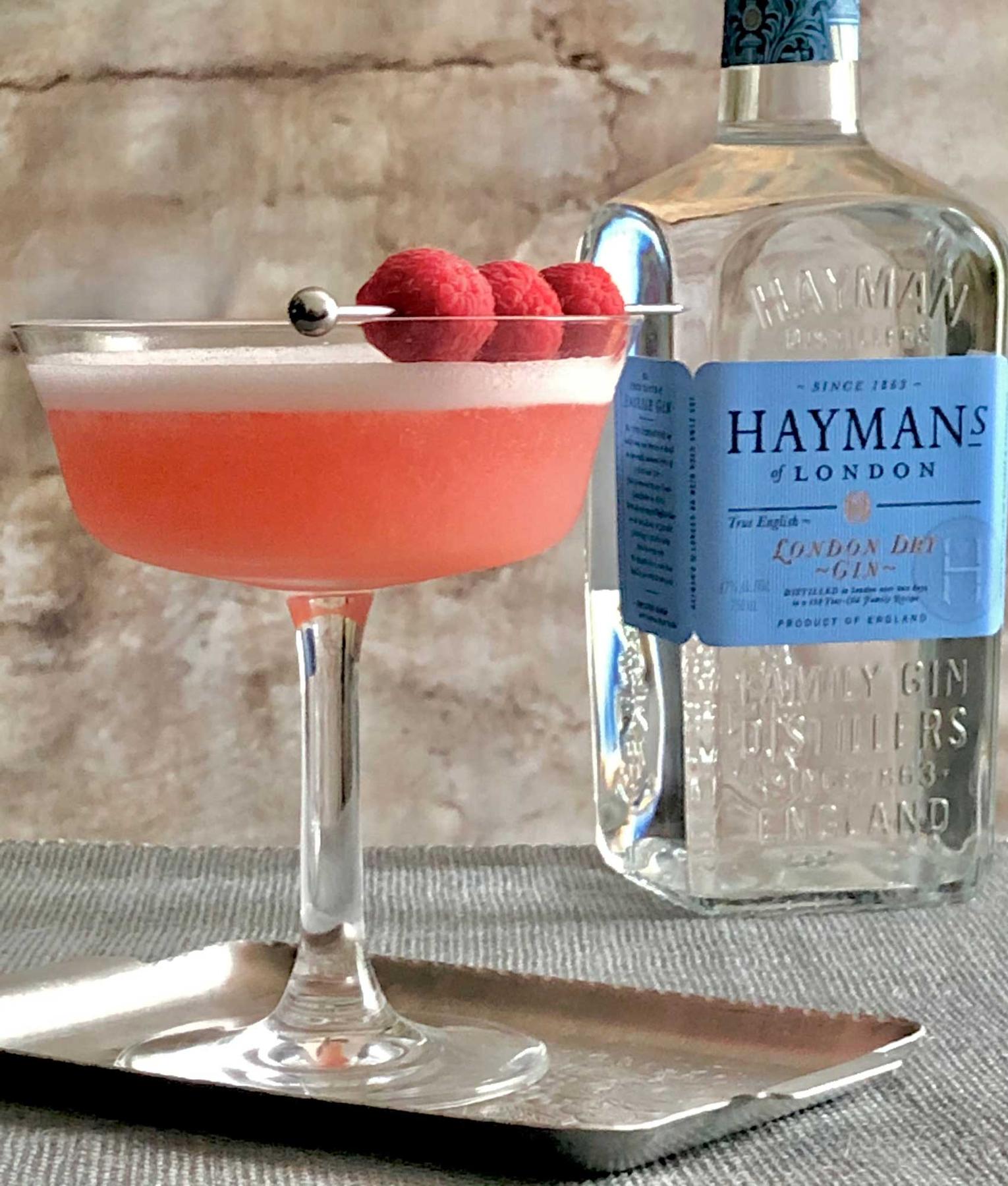 An example of the Clover Club, the mixed drink (drink), Adapted by Julie Reiner, NYC, featuring Hayman’s London Dry Gin, egg white, lemon juice, Dolin Dry Vermouth de Chambéry, raspberry syrup, and raspberries; photo by Lee Edwards