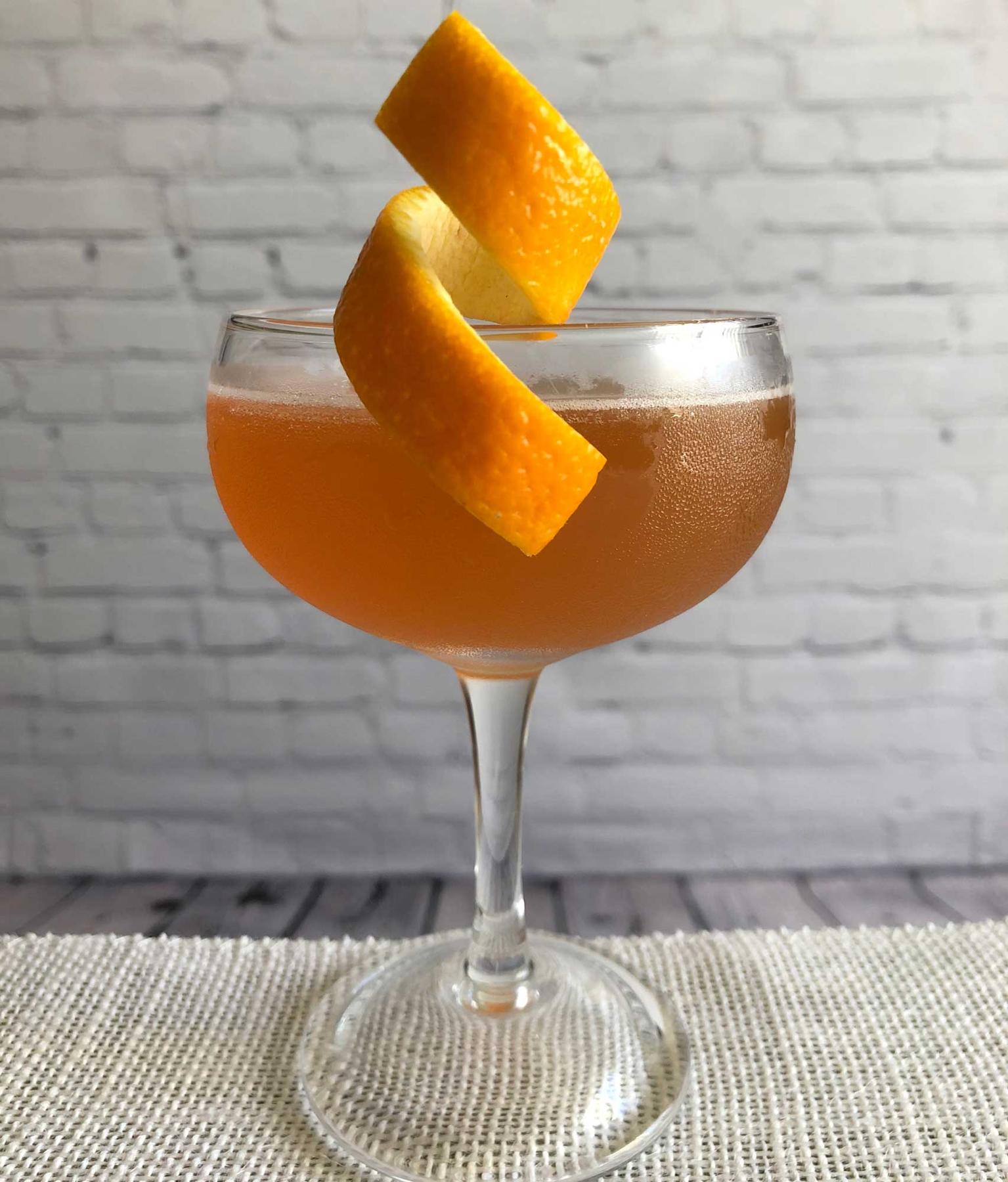 An example of the Diki-Diki, the mixed drink (drink), by Savoy Cocktail Book, featuring calvados, KRONAN Swedish Punsch, grapefruit juice, simple syrup, and orange twist; photo by Lee Edwards