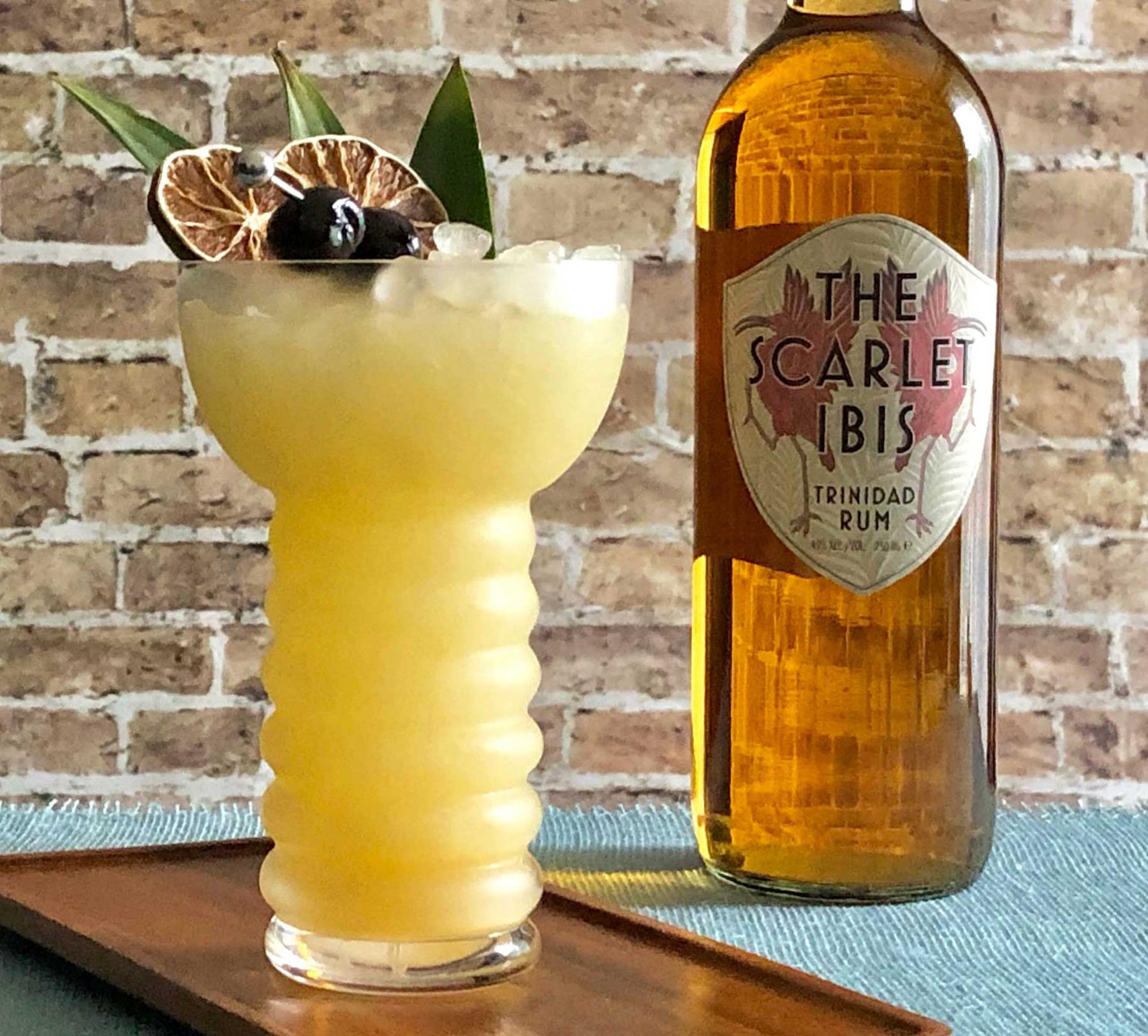 An example of the The Beachbum, the mixed drink (drink), by John Deragon, PDT, New York City, featuring The Scarlet Ibis Trinidad Rum, light rum, pineapple juice, lime juice, Rothman & Winter Orchard Apricot Liqueur, orgeat, pineapple leaf, maraschino cherry, and lime wheel