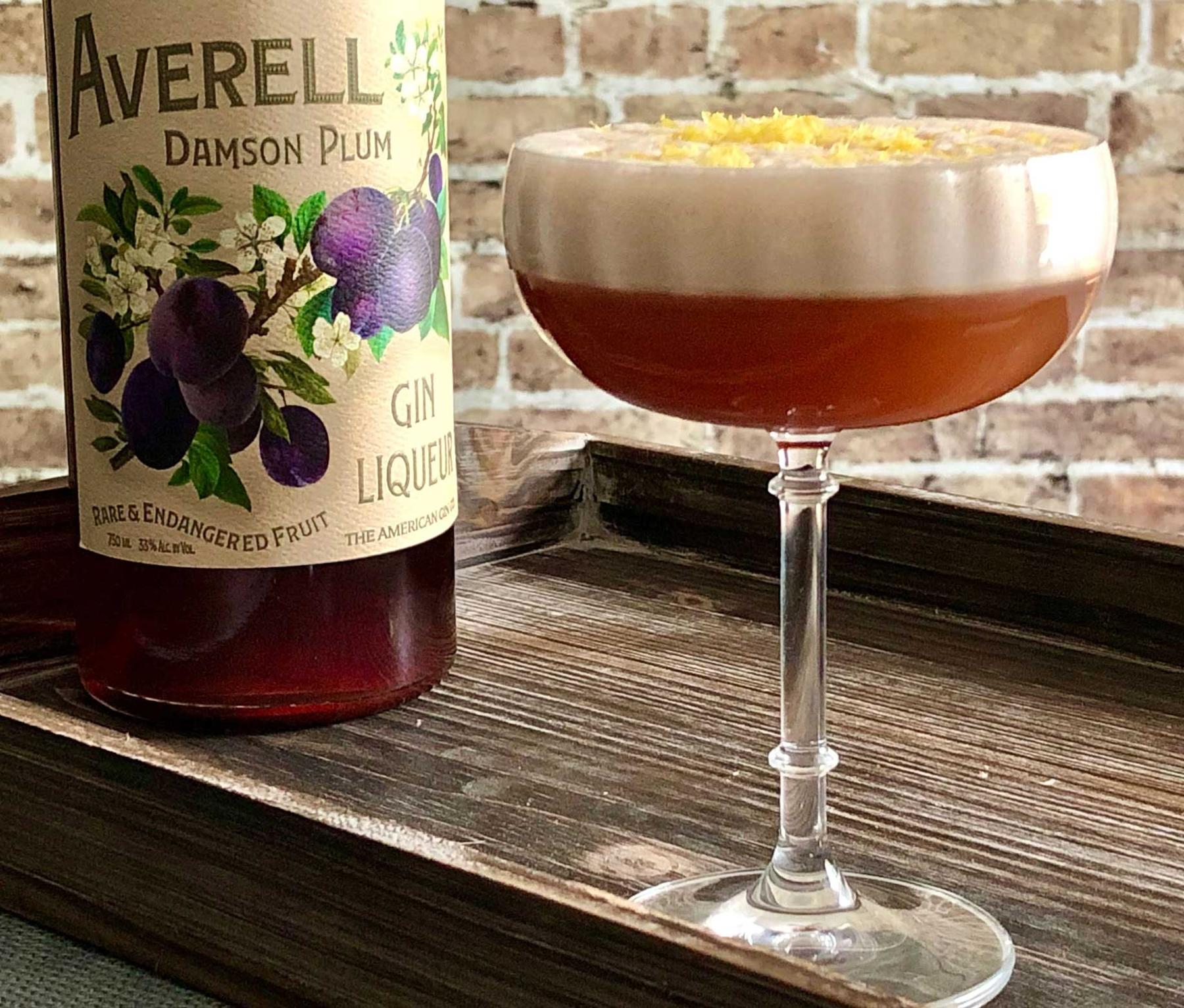 An example of the Clingstone Club, the mixed drink (drink) featuring Averell Damson Plum Gin Liqueur, egg white, simple syrup, lemon juice, Nux Alpina Walnut Liqueur, and lemon twist; photo by Lee Edwards