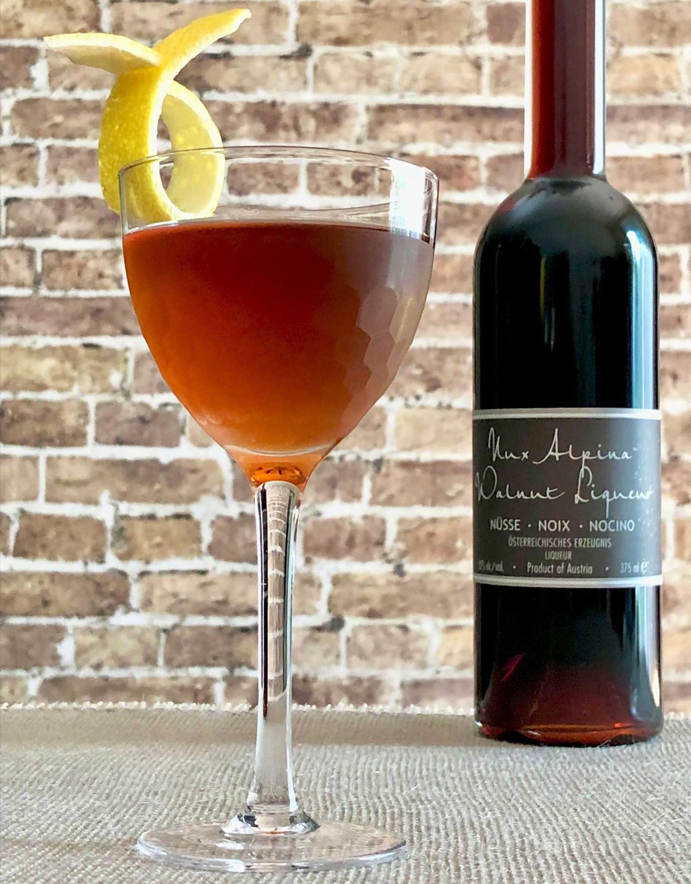 An example of the Green Team, the mixed drink (drink) featuring irish whiskey, Dolin Blanc Vermouth de Chambéry, Nux Alpina Walnut Liqueur, and lemon twist; photo by Lee Edwards