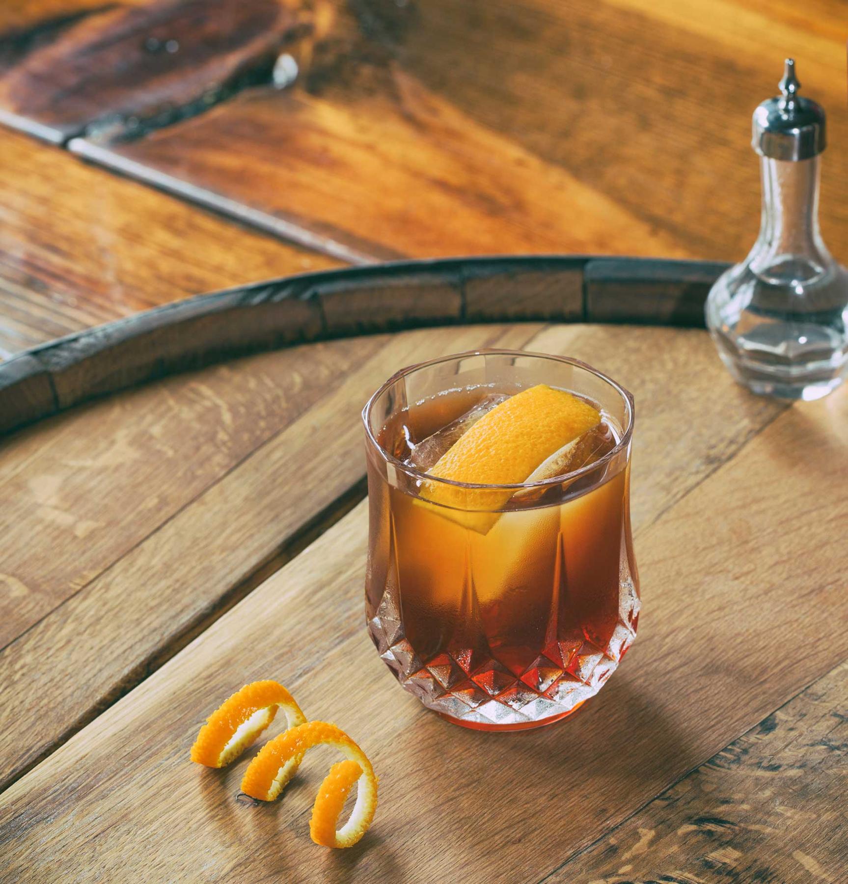 An example of the The Niall, the mixed drink (drink), by Ryan Maybee, Manifesto and The Rieger, Kansas City, featuring J. Rieger & Co. Kansas City Whiskey, Cocchi Vermouth di Torino ‘Storico’, Aperitivo Cappelletti, Regans’ No. 6 Orange Bitters, Kubler Absinthe Supérieure, large ice cube, and grated orange peel; photo by Brandon Cummins