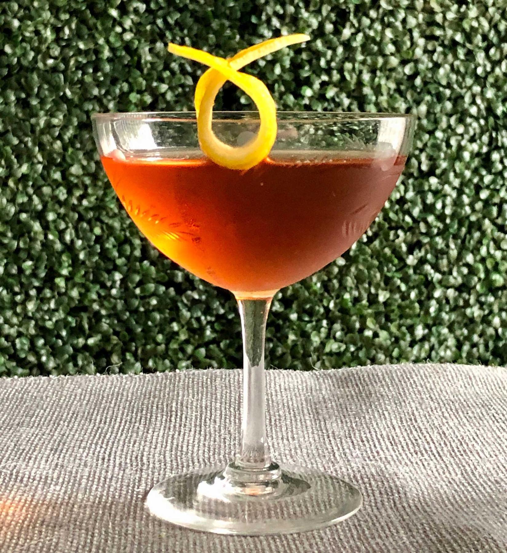 An example of the Mr. Burns, the mixed drink (drink), by Jon DeRosa, Oldfields Liquor Room, Los Angeles, featuring Dewar’s White Label, Cocchi Vermouth di Torino ‘Storico’, Zirbenz Stone Pine Liqueur of the Alps, and lemon twist; photo by Lee Edwards