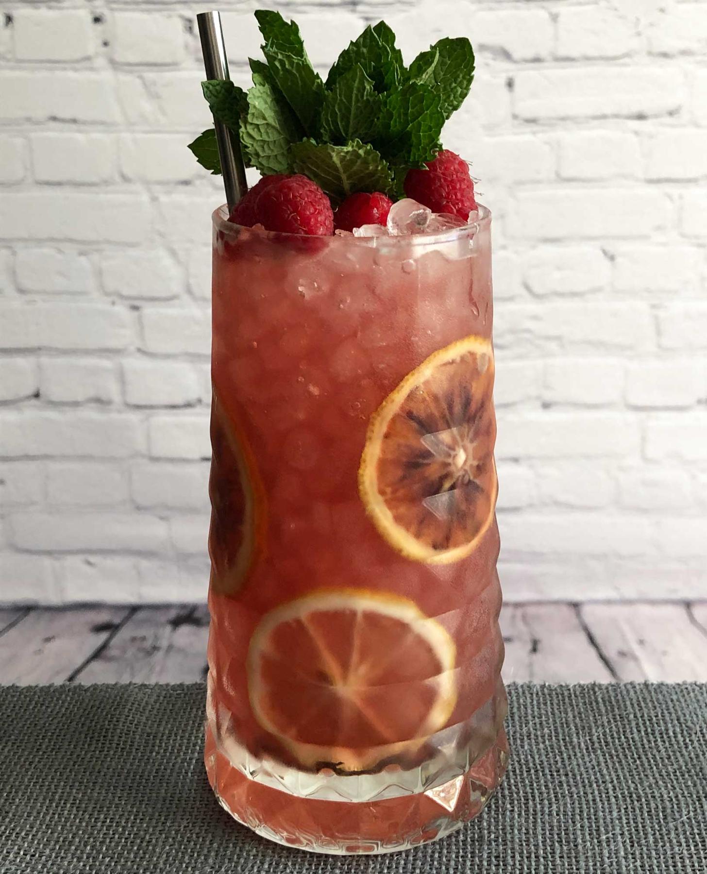 An example of the Rosa Cobbler, the mixed drink (drink) featuring Cocchi Americano Rosa, simple syrup, orange wheel, lemon wheel, berry, and sprig of mint; photo by Lee Edwards